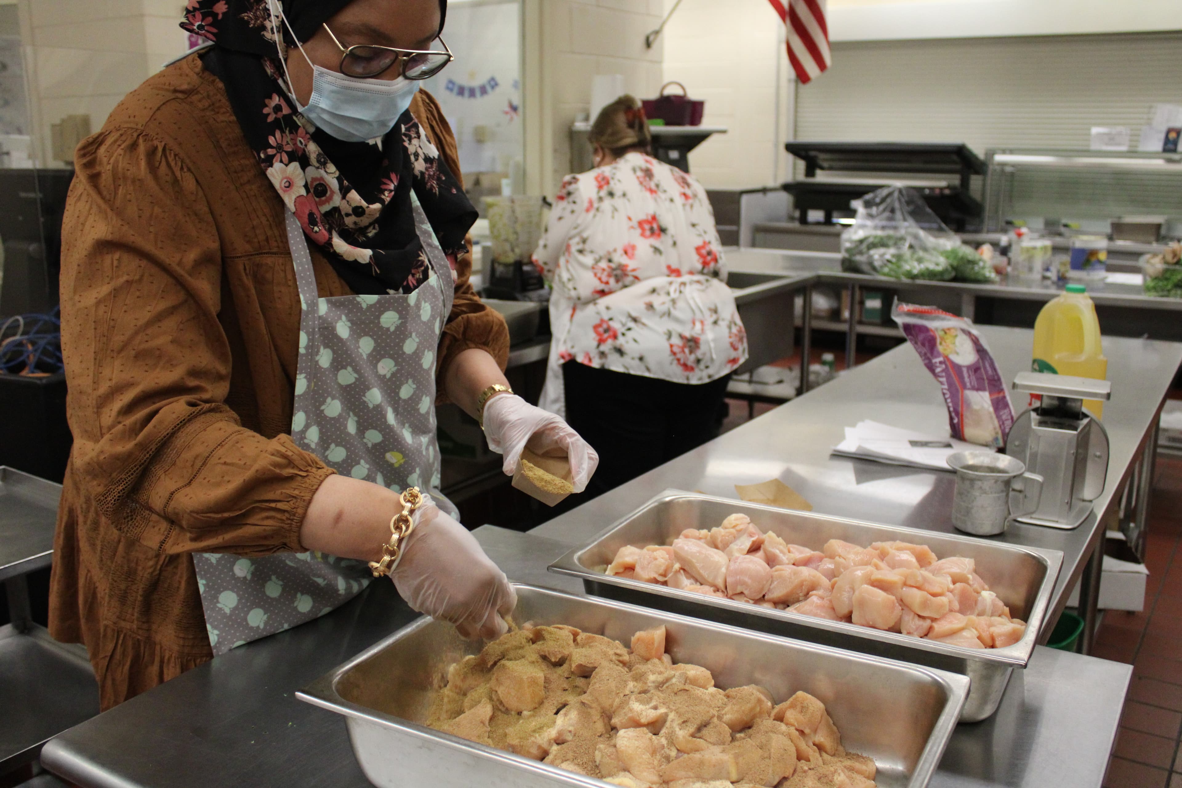 Chef Khadija Ahmed sprinkles spices on sliced chicken breasts that will be used in a stew inspired by North African cuisine.
