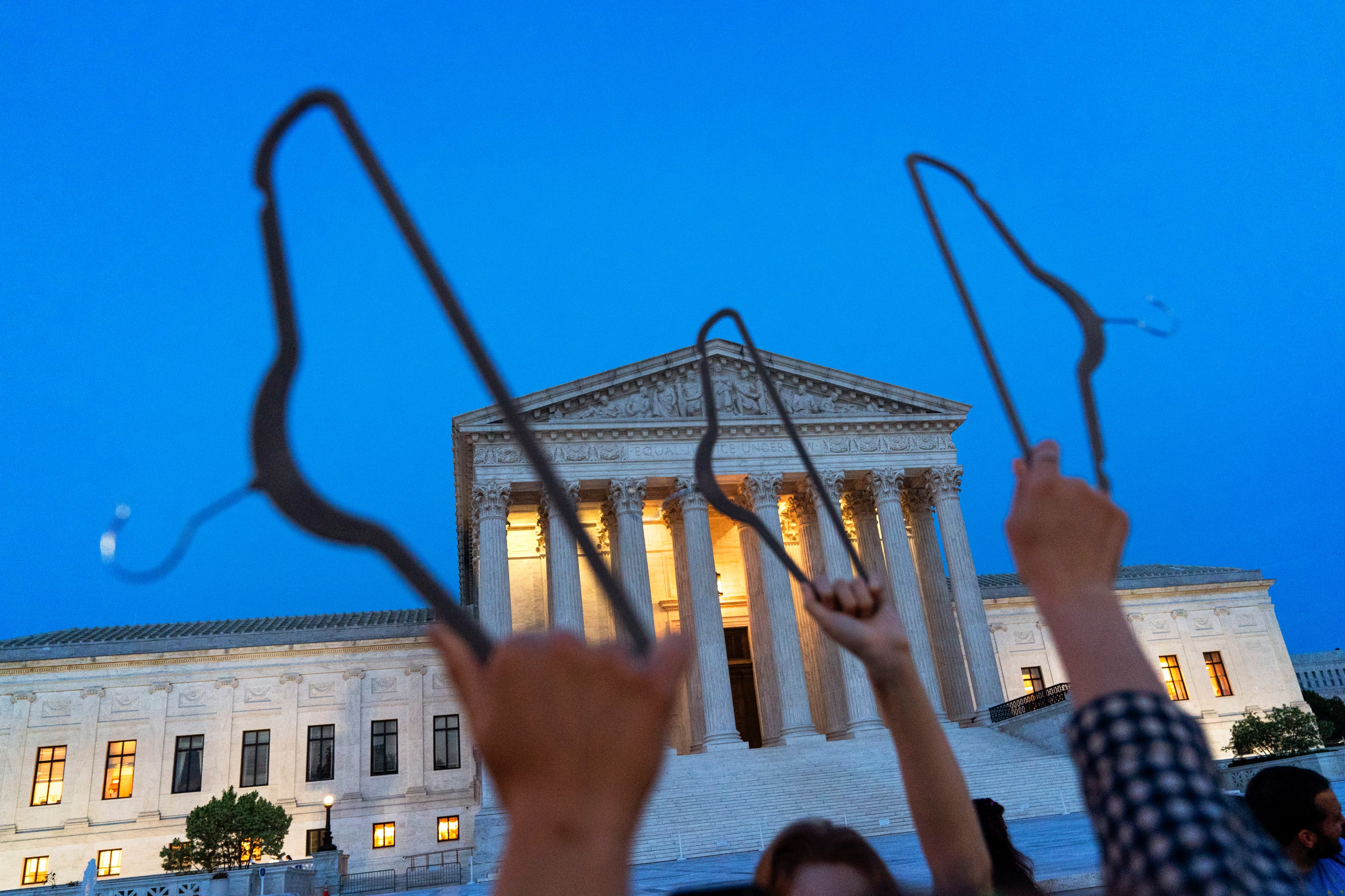 Demonstrators hold coat hangers in the air as they protest outside of the U.S. Supreme Court in May 2022.