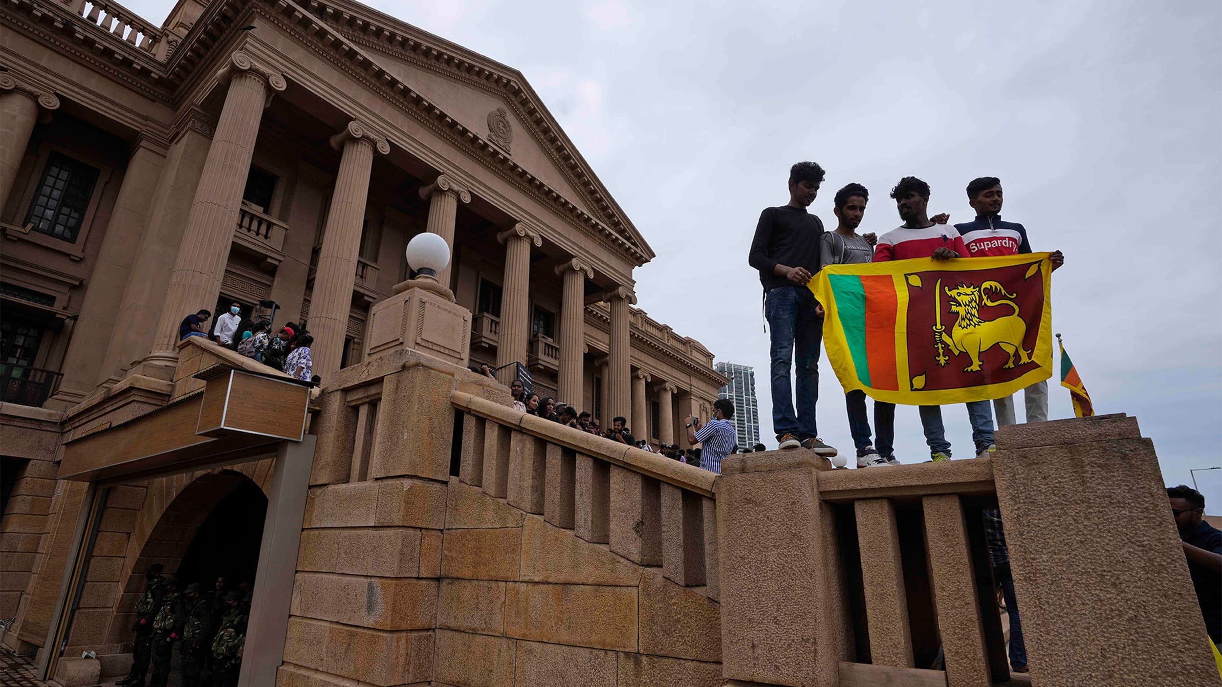 People stand holding a national flag at President Gotabaya Rajapaksa's office on the second day after it was stormed in Colombo, Sri Lanka
