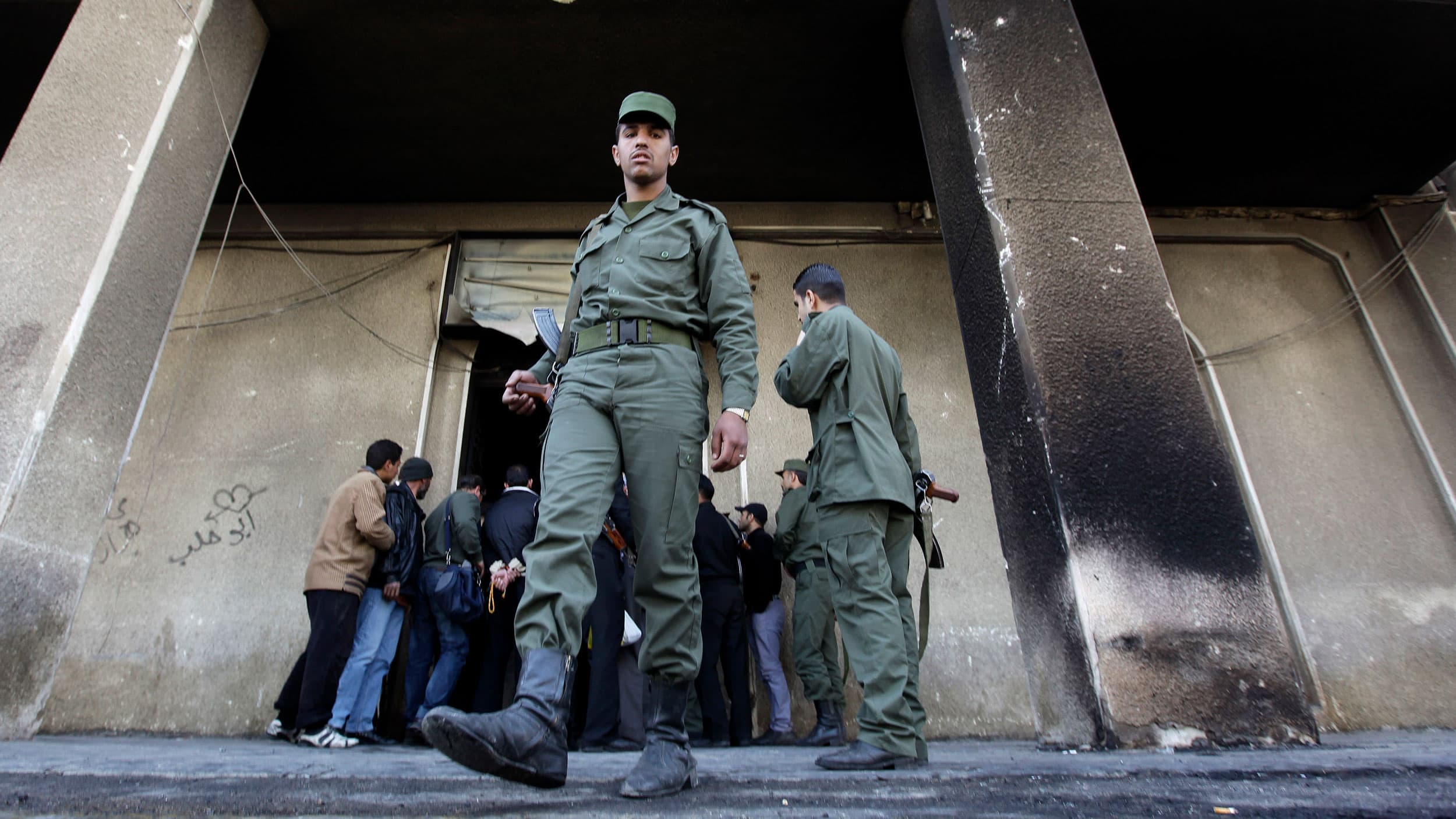 In this March 21, 2011, file photo, a Syrian soldier steps out of the burned courthouse that was set on fire by anti-government protesters in the southern city of Daraa, Syria.