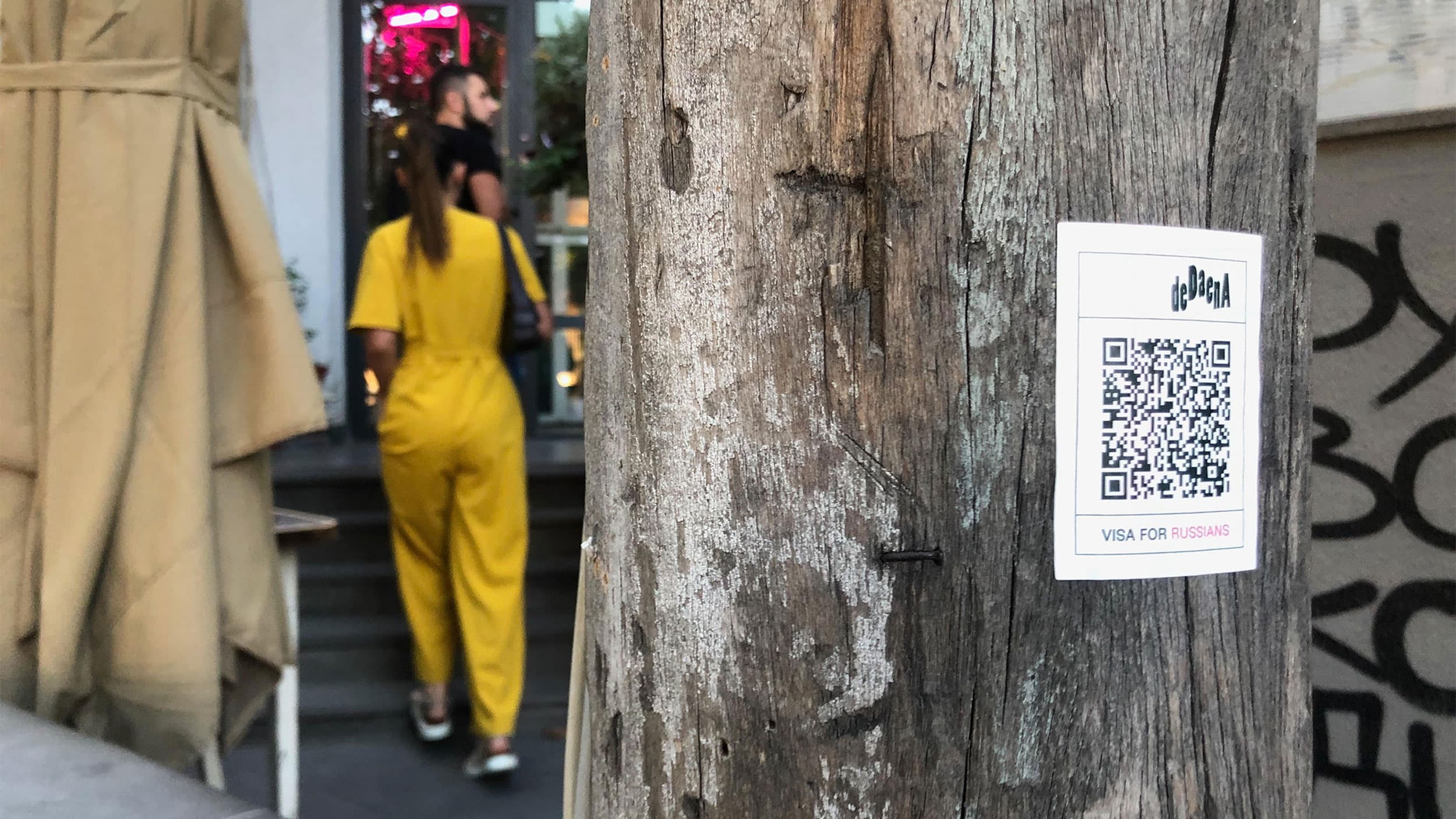 Customers walk into the Dedaena Bar in Tbilisi past a QR code notice