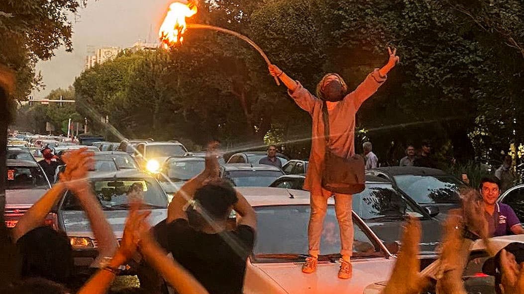 A woman in Tehran climbs onto a car and sets her hijab ablaze.