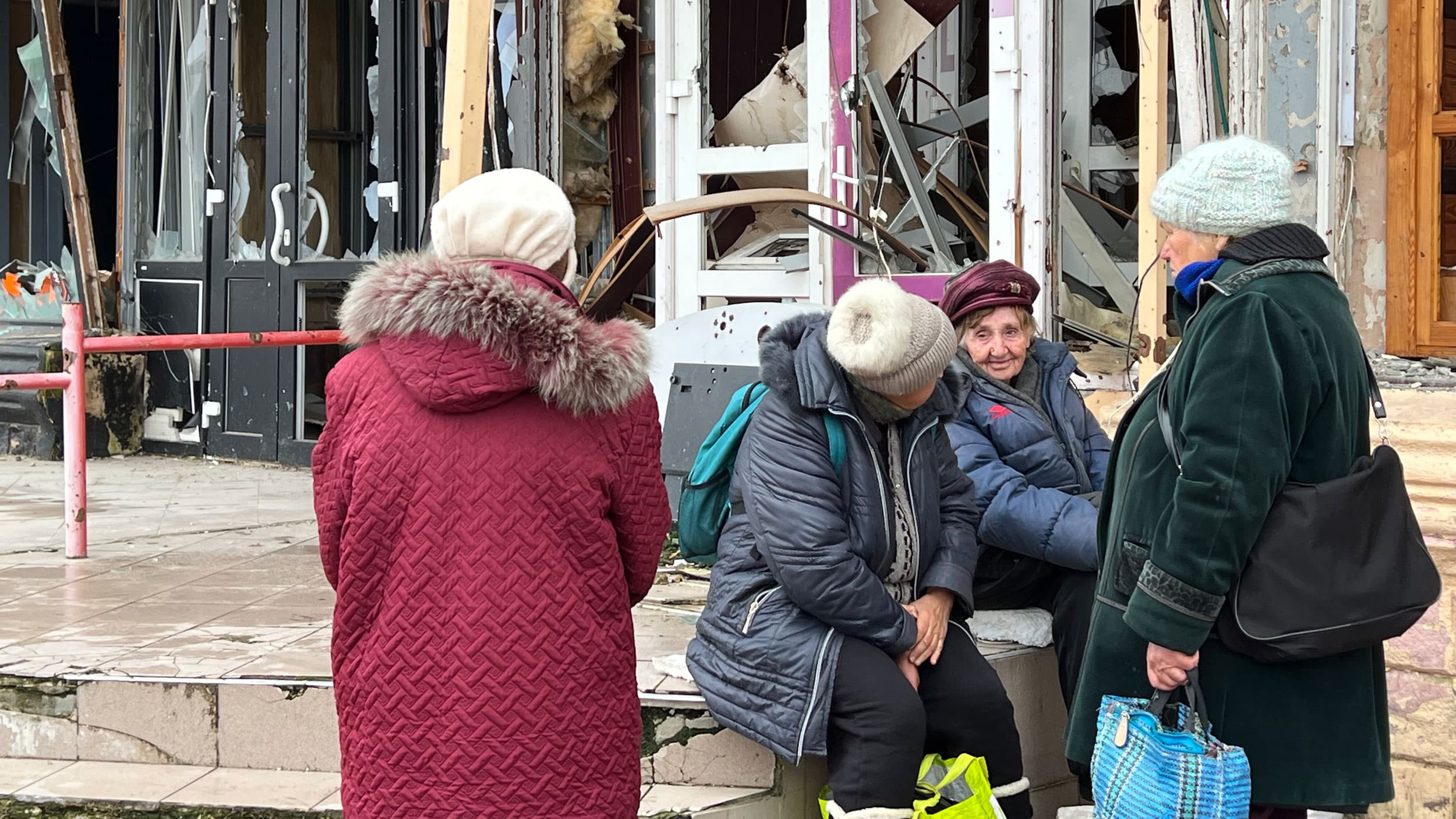 Residents of Izium take a break next to some shattered stores. Most of the residents left but some elderly stayed behind.