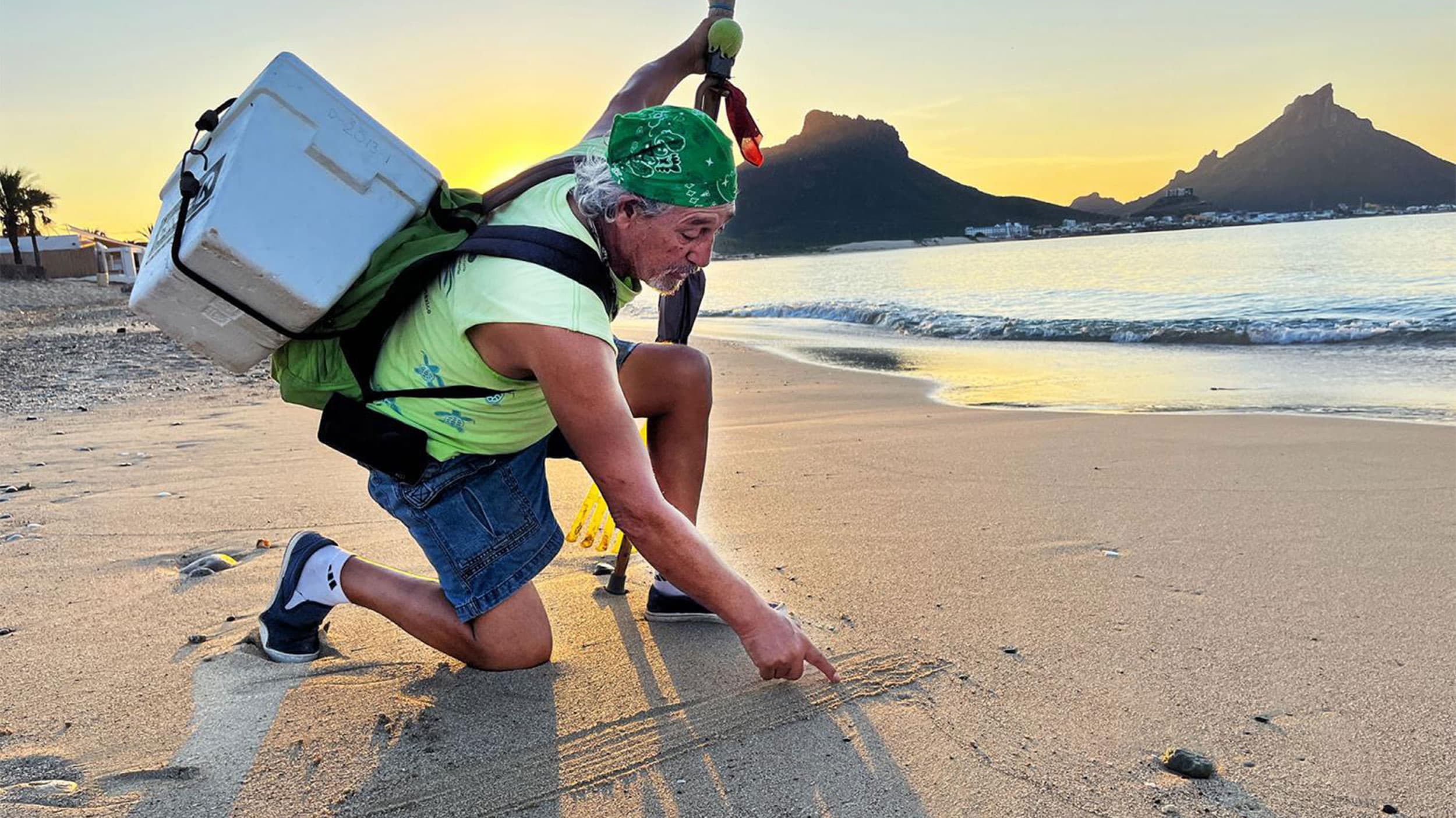 Antonio Lopez makes markings in the sand to show what sea turtle tracks look like.