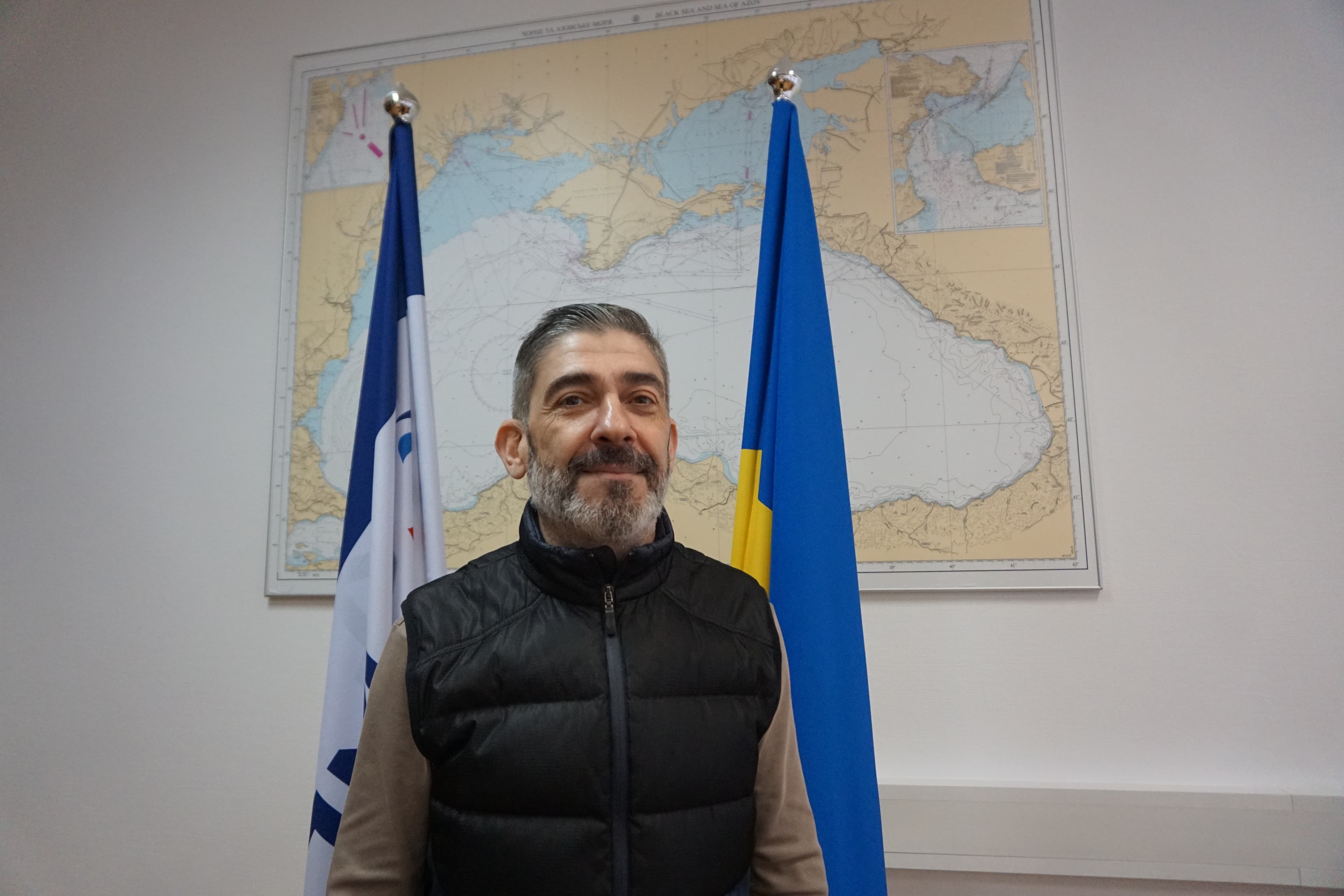 man standing near flags and a map