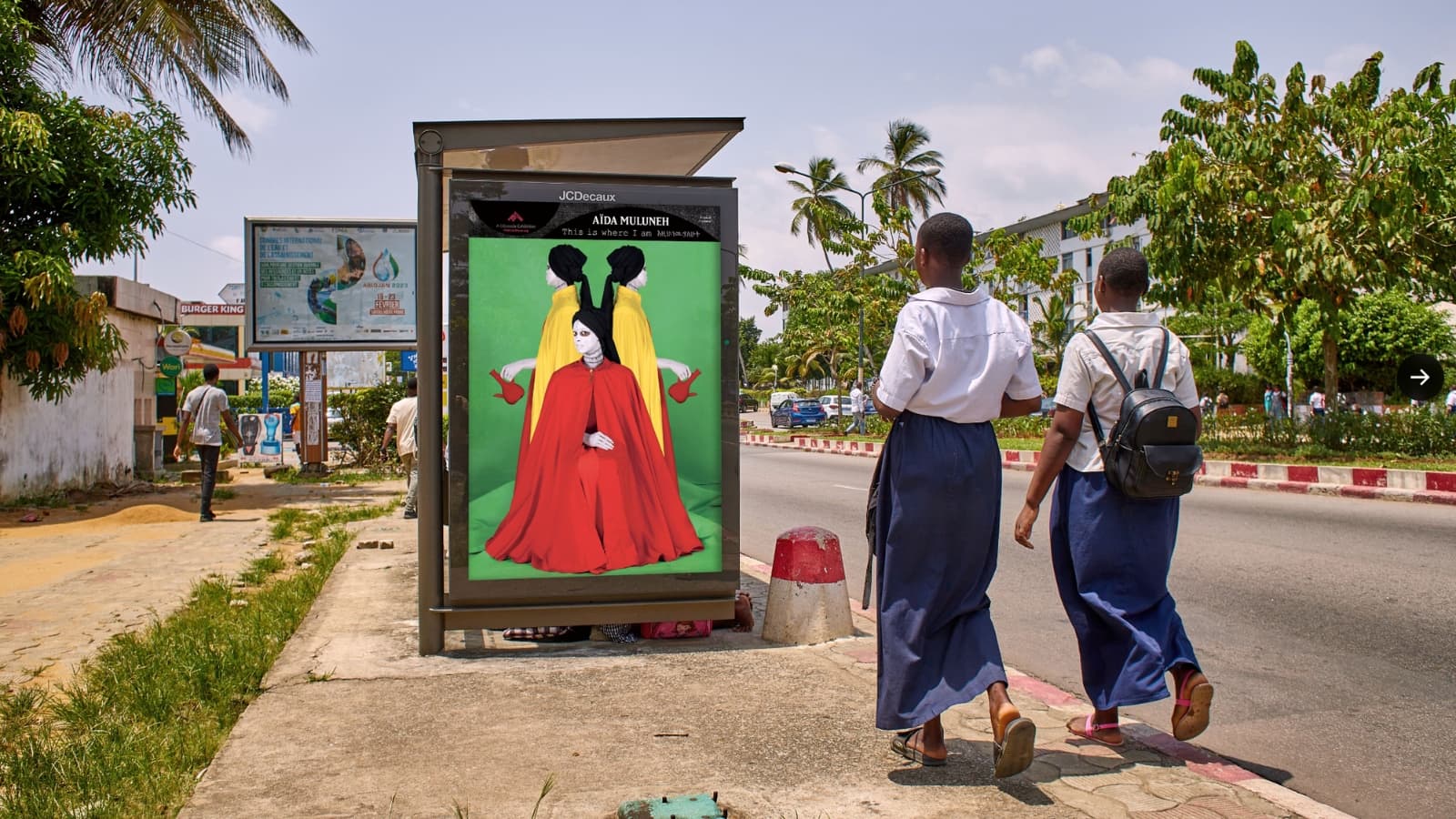 A photograph of three women with standing in front of a green background is shown in a bus stop.