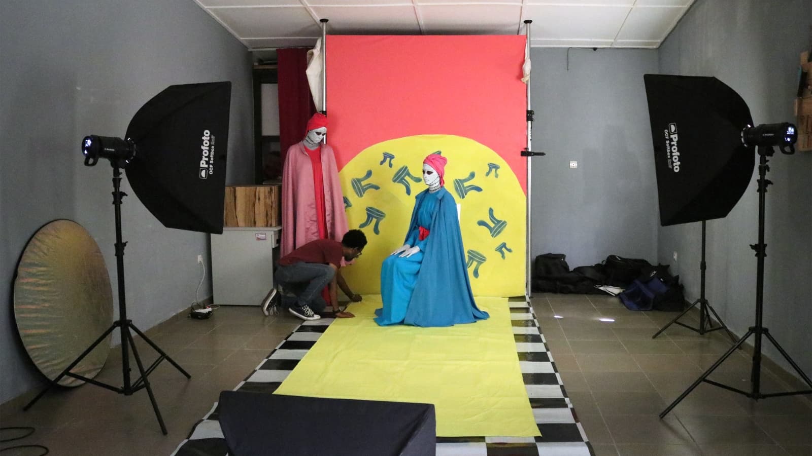 Lights are on on a photoshoot set. The model is sit down ready for the photo.