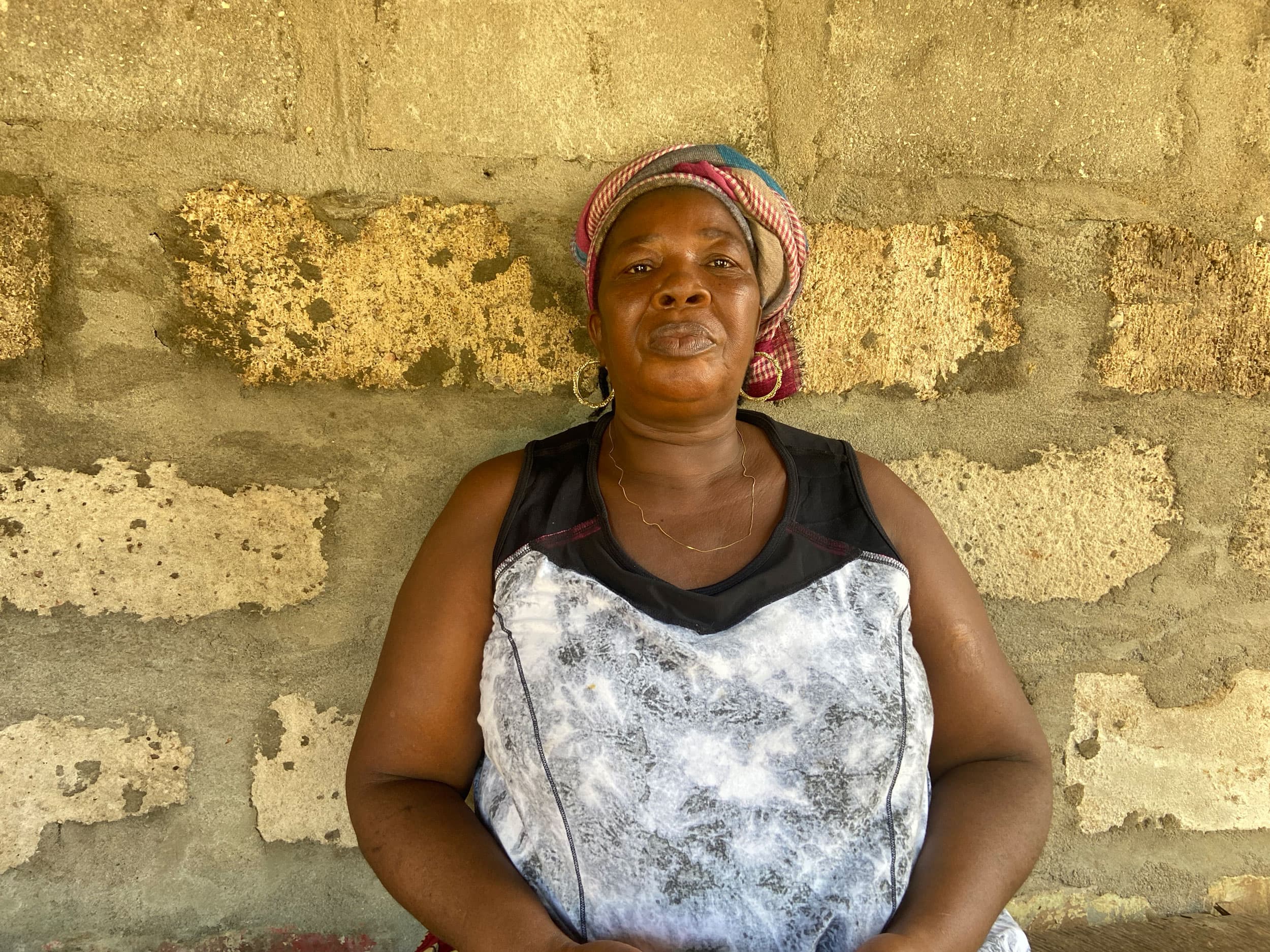 Food vendor Hande Sesay stands against a brick wall wearing a sleeveless dress.