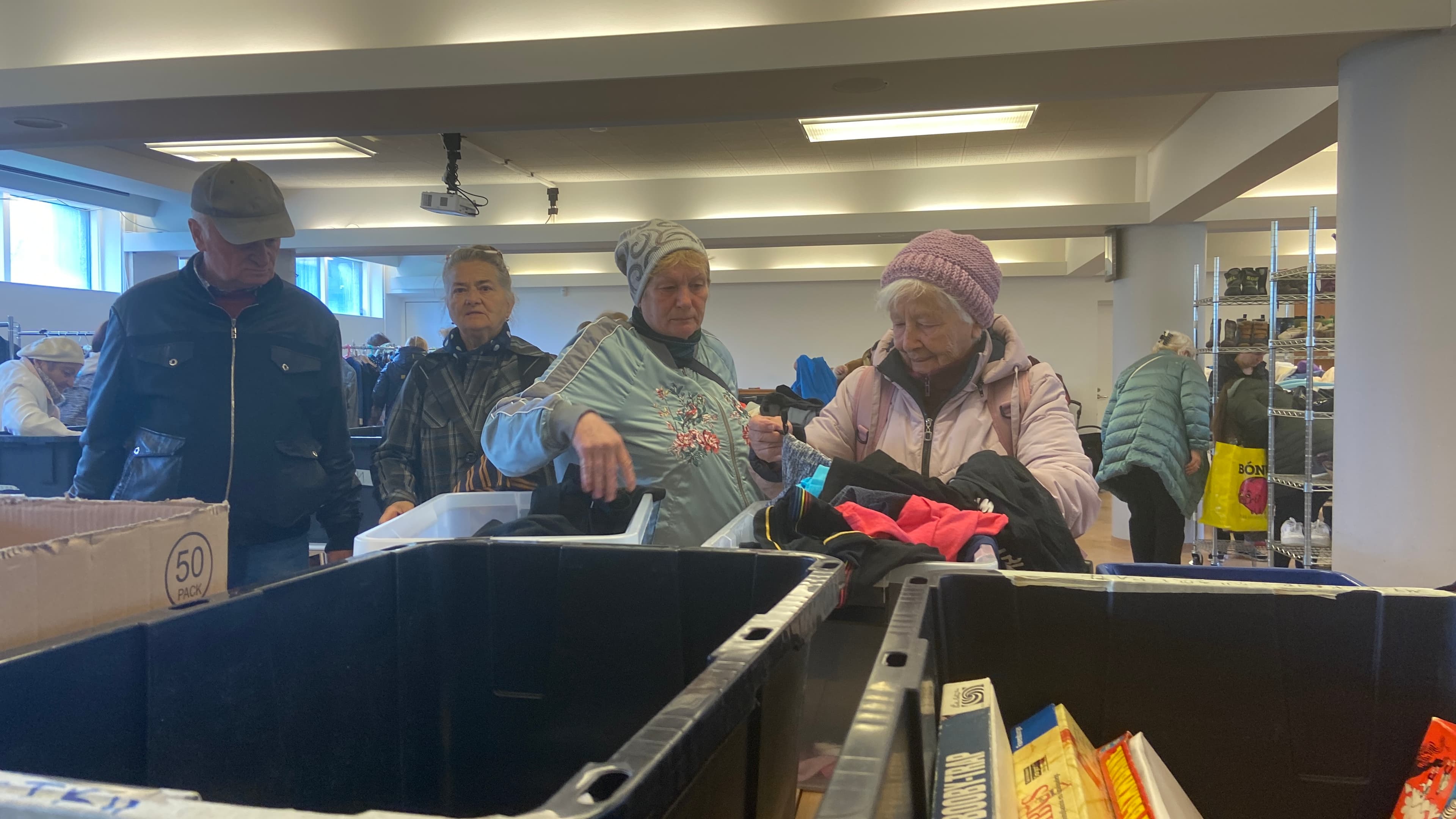 four individuals sort through bins of clothes and games