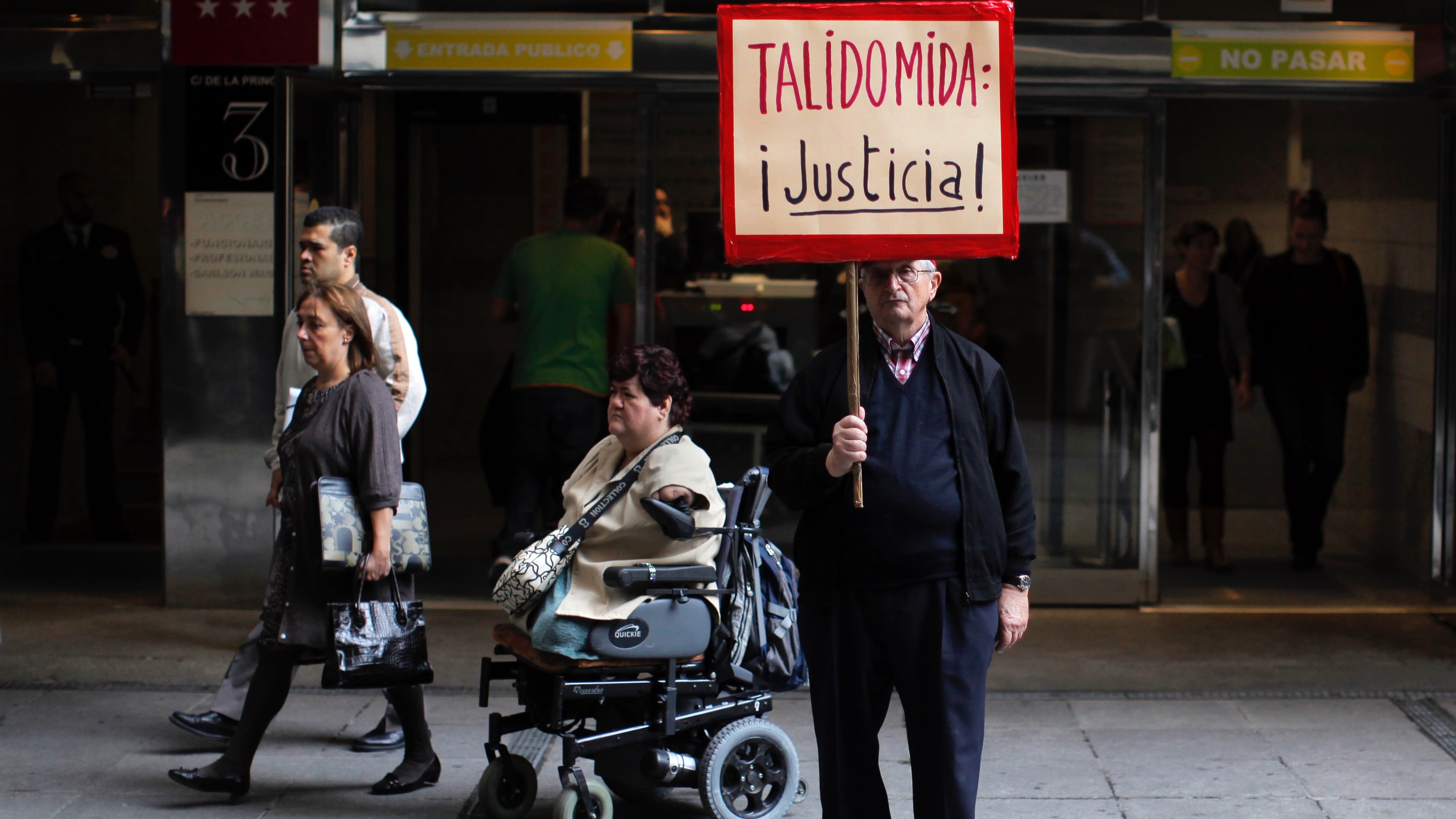man holding a sign with people passing by in the background