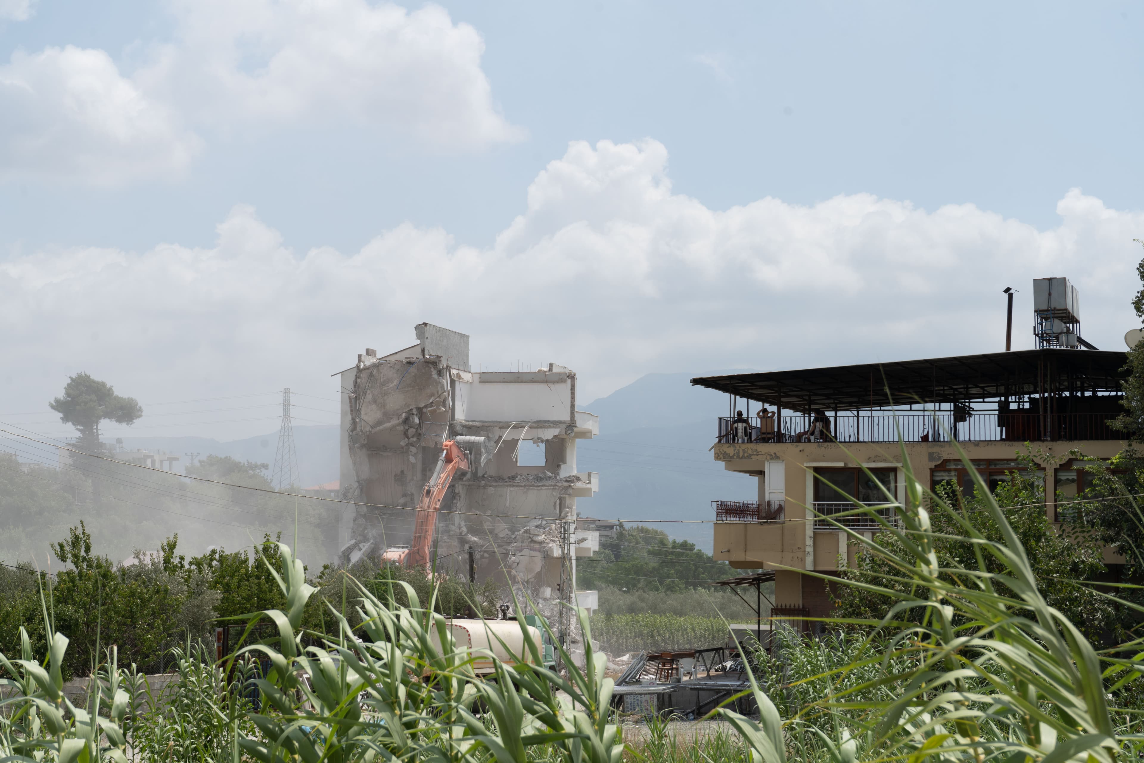From their terrace, a family watches a building next door get torn down. Asbestos wasn’t banned in Turkey until 2010, and environmentalists fear the dust created by earthquake debris is toxic.