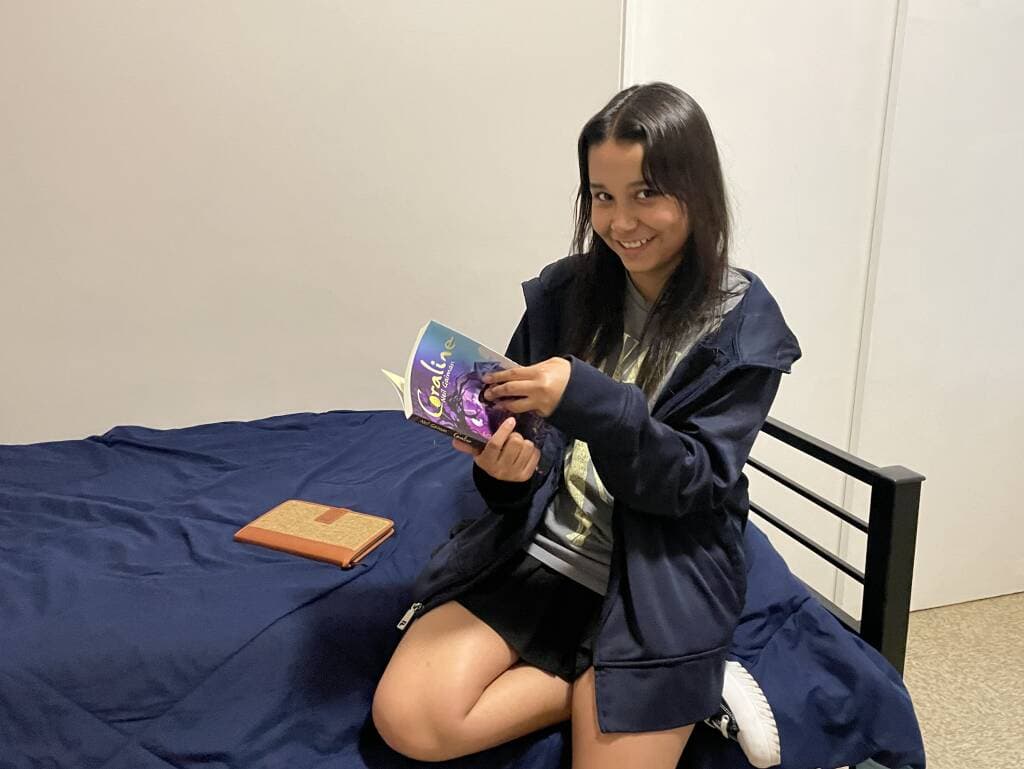 Zhayreth Torres shows GBH reporters her room and a book she is reading for eighth grade English.