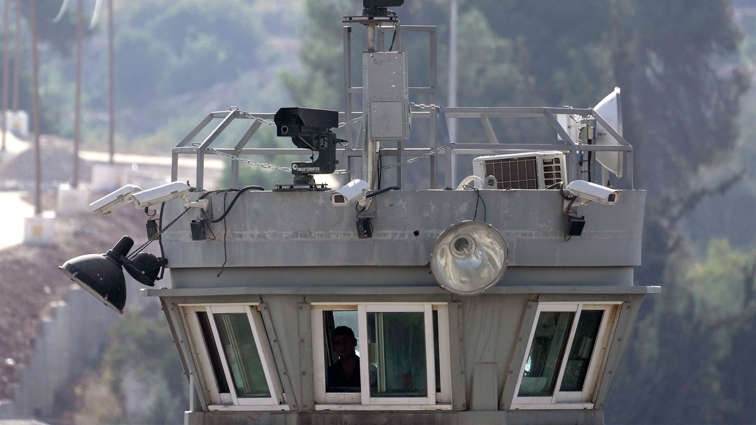 Two robotic guns sit atop a guard tower bristling with surveillance cameras pointed at the Aroub refugee camp in the West Bank, Oct. 6, 2022.