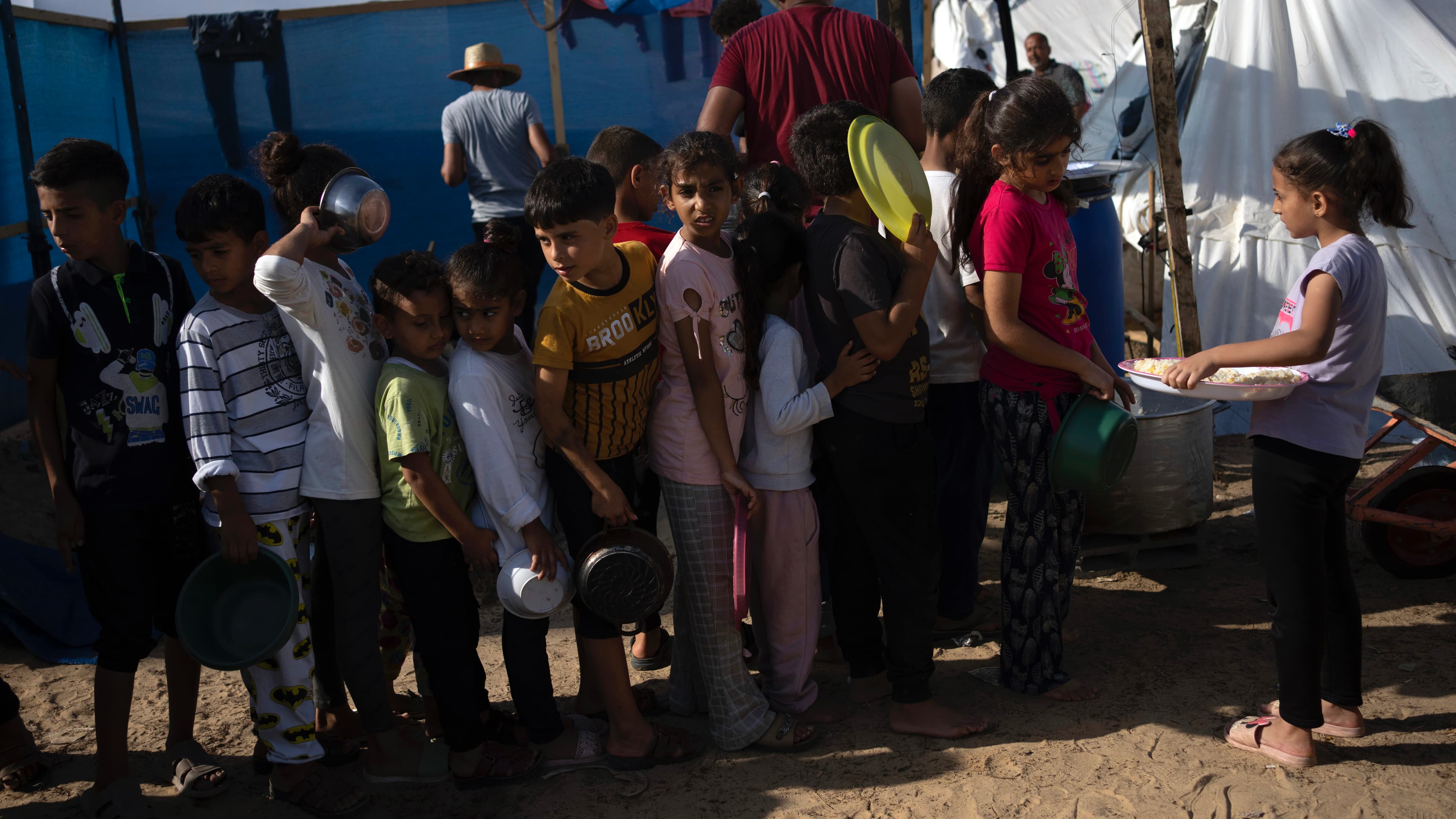 Children stand in a line waiting for food portions