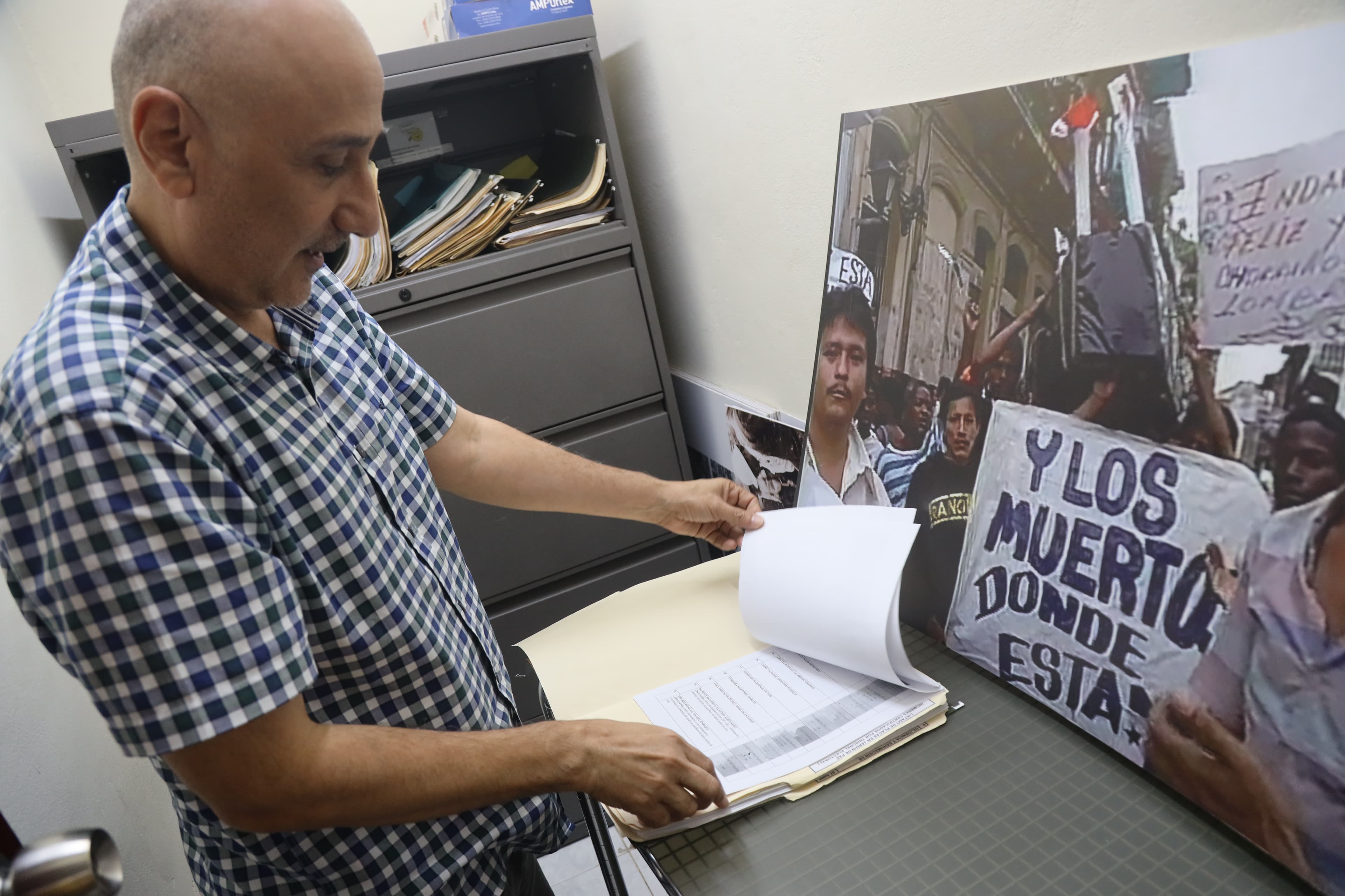 Older man in checkered shirt looking through a folder