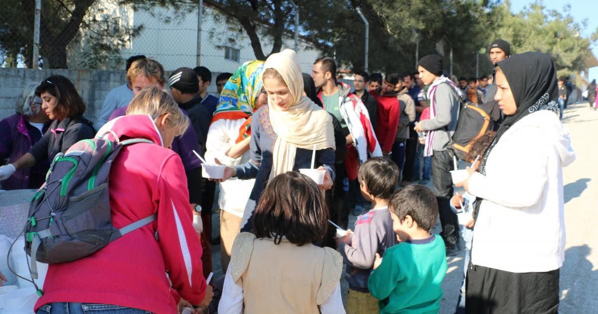 A young Afghan woman and children have just received their breakfasts, rice pudding from Manolis Tzanetos's catering company.