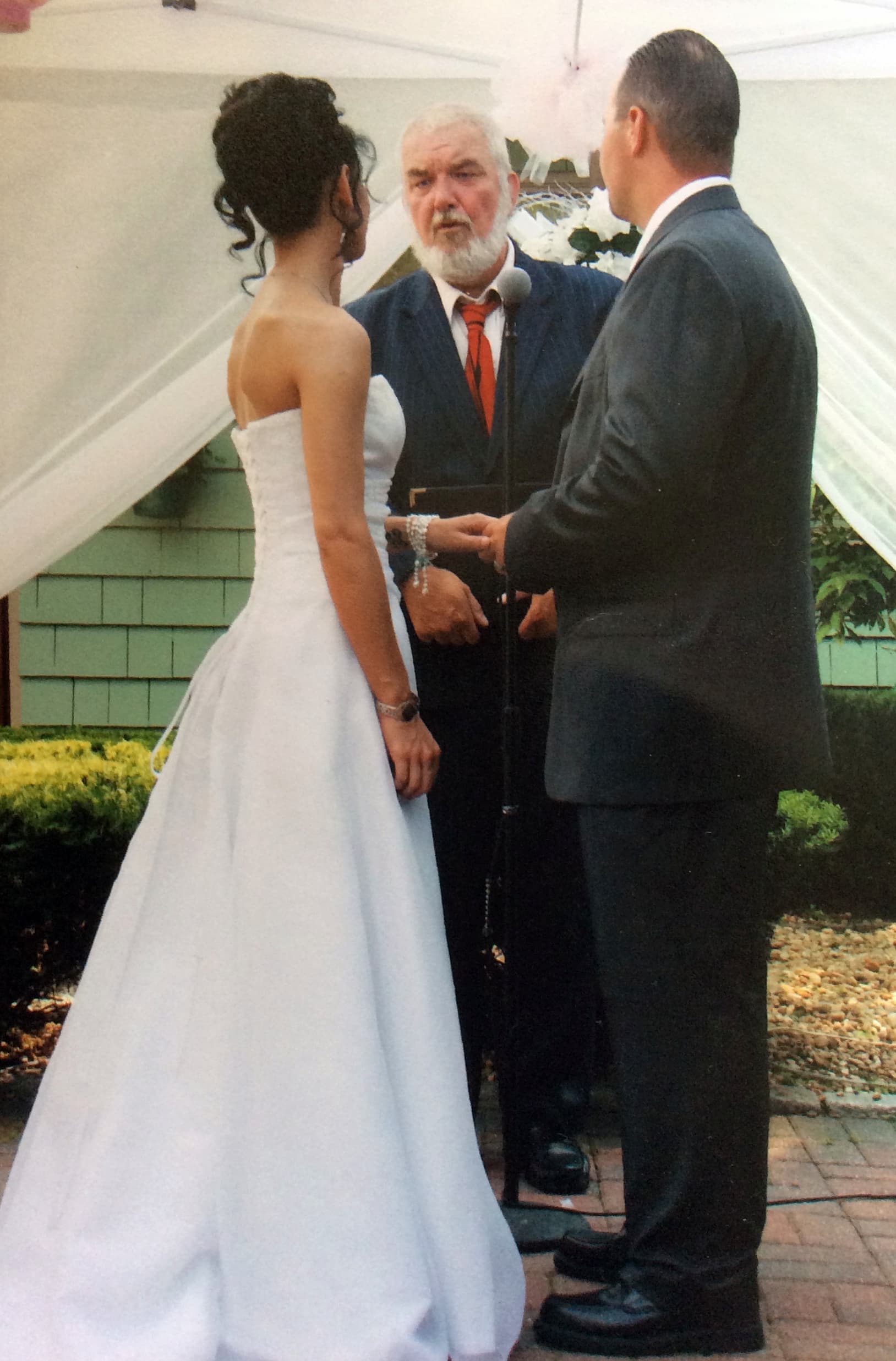 Wedding photo with couple looking at officiant