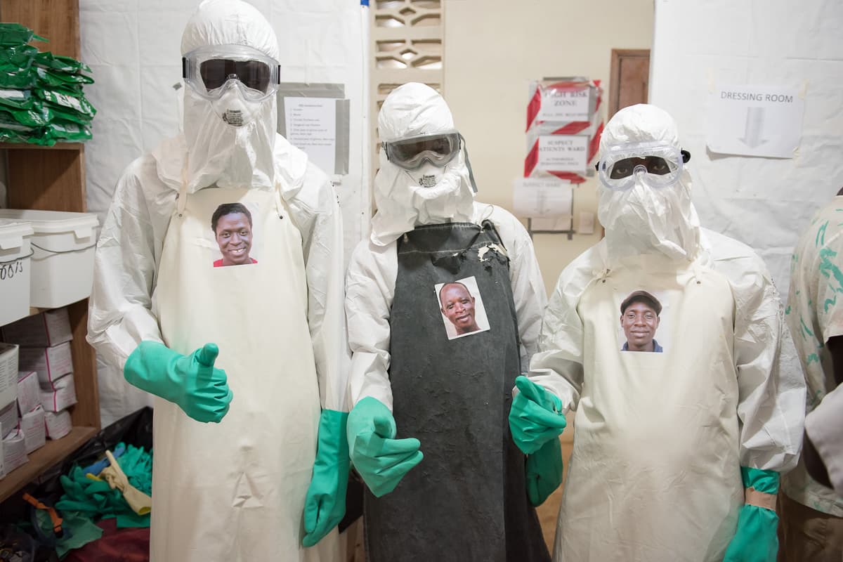 Health workers Morris Zolu, Kaifouba Kamara, and Joseph Walatee wearing their portraits.
