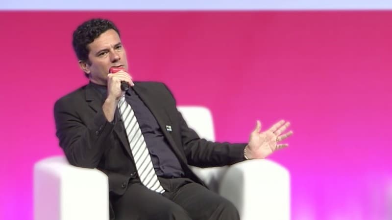 The judge with a microphone in front of pink background