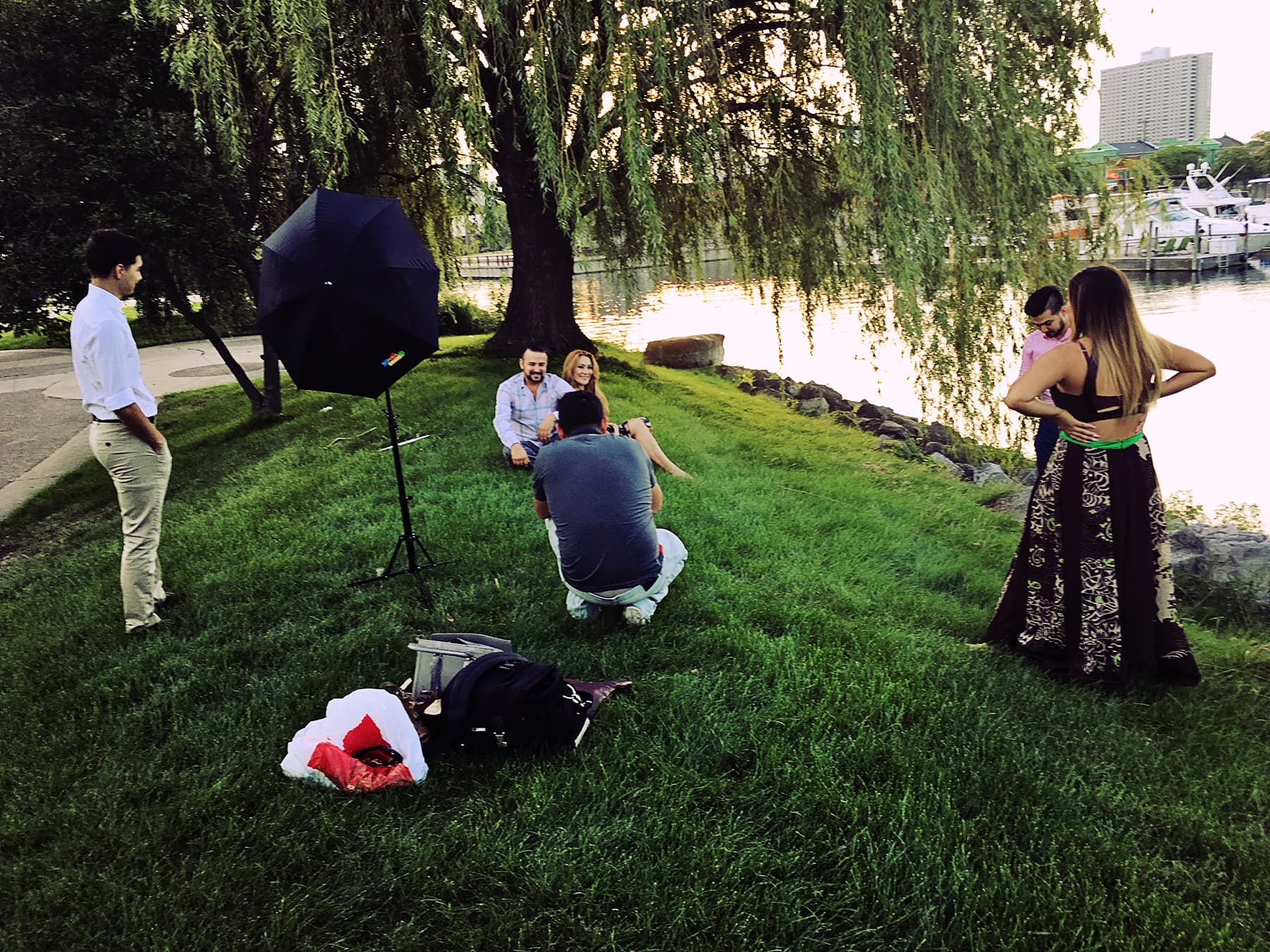 Looking from back of photographer as he instructs family, with umbrella, tripod nearby