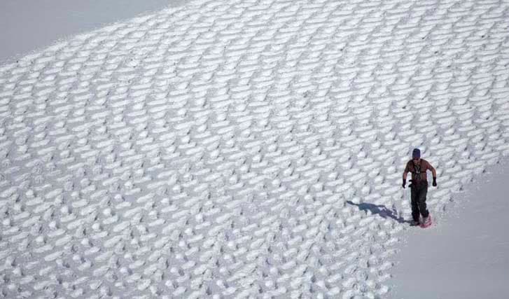 Simon Beck snowshoeing in circles to create image of a wolf howling at the moon.