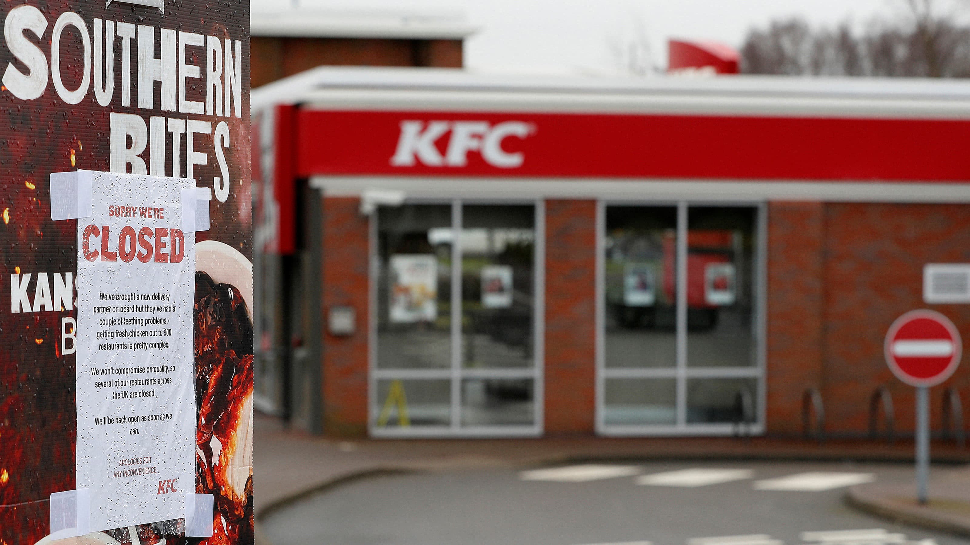 A paper sign is taped on top of a KFC ad telling customers that the restaurant is closed.