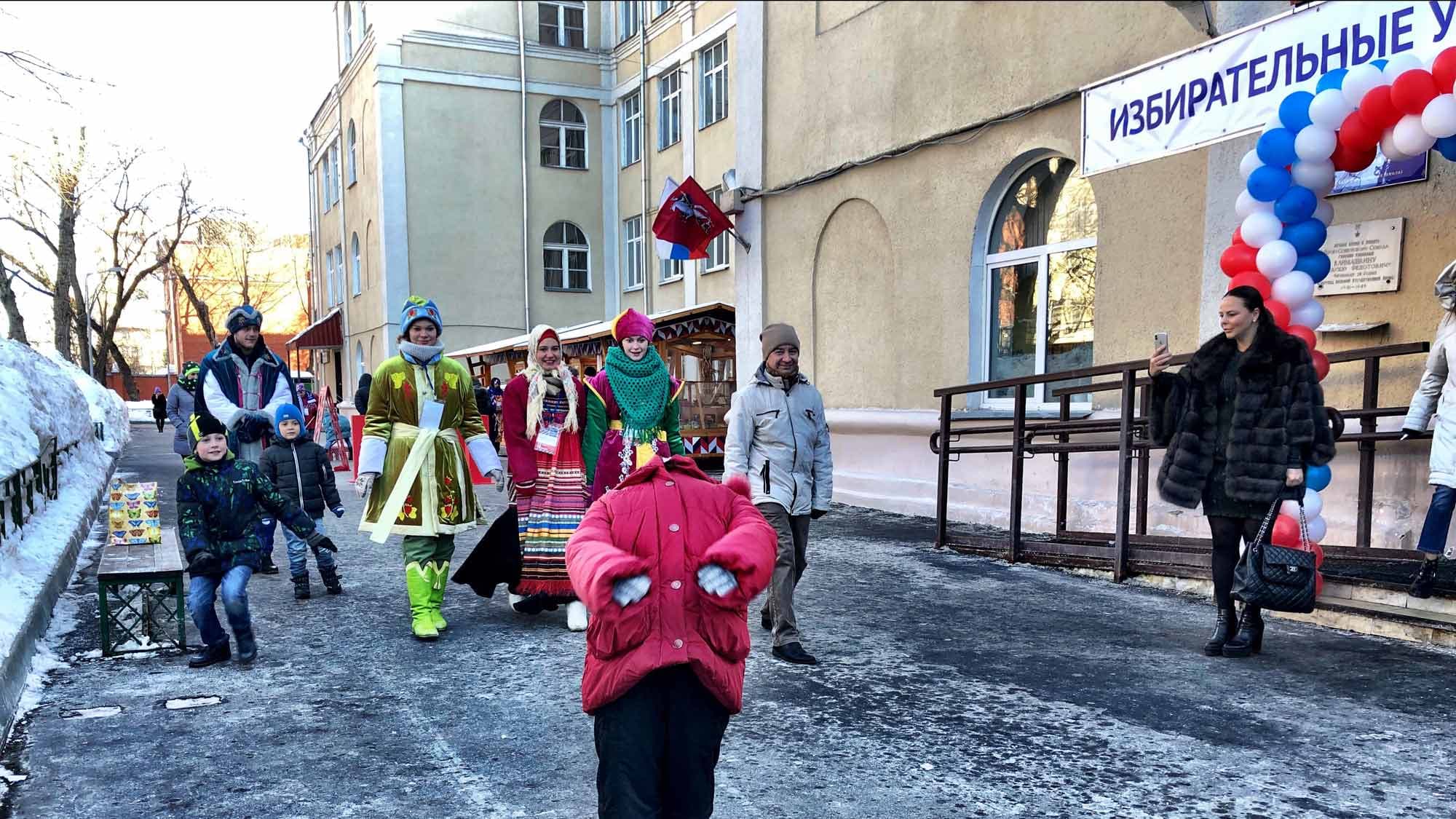 A person is bent backward as a bag flies overhead during a game outside a polling place.