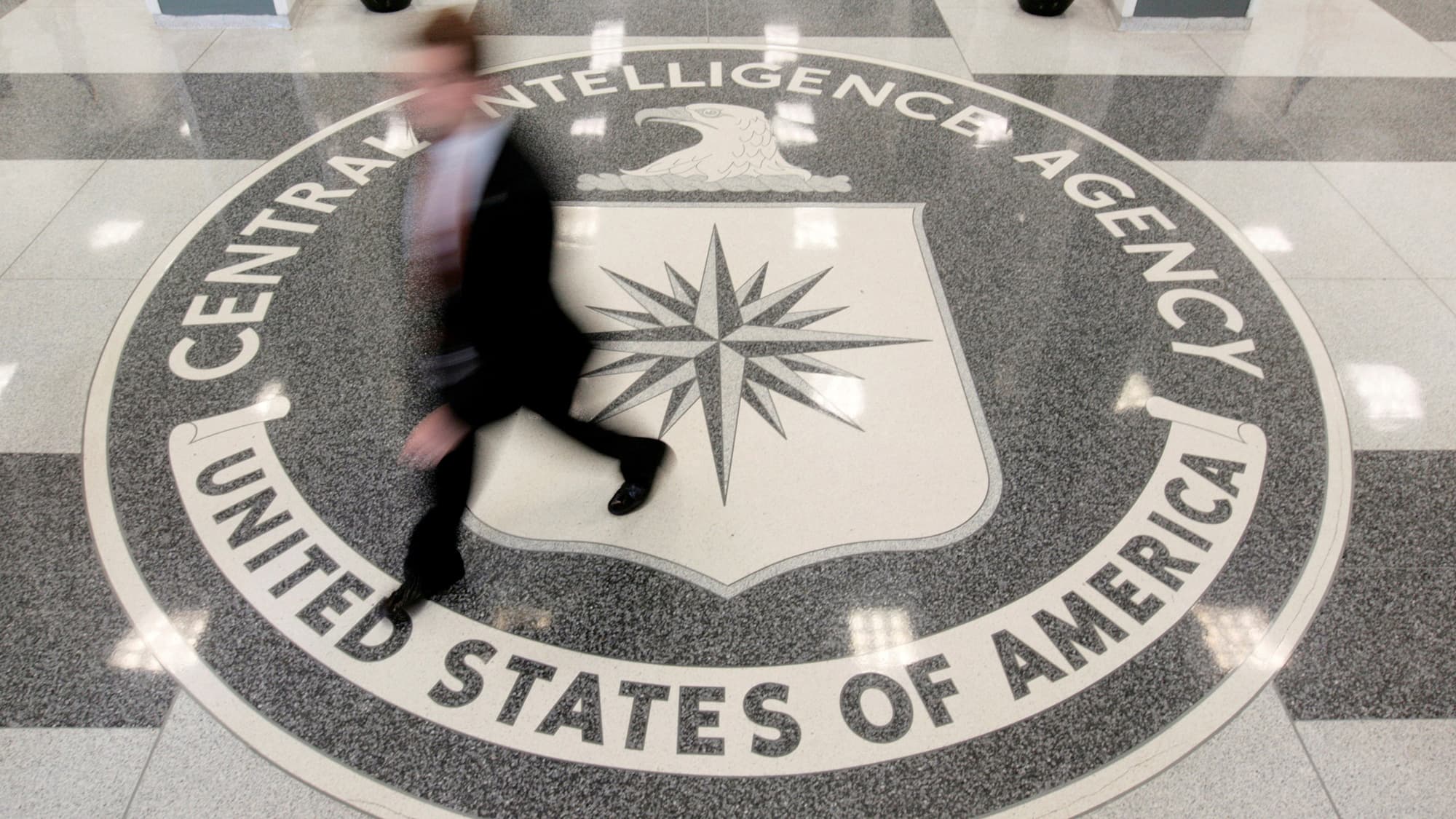 A man's image is blurred as he walks across a giant marble seal in the floor of the CIA headquarters in Langley, Virginia.