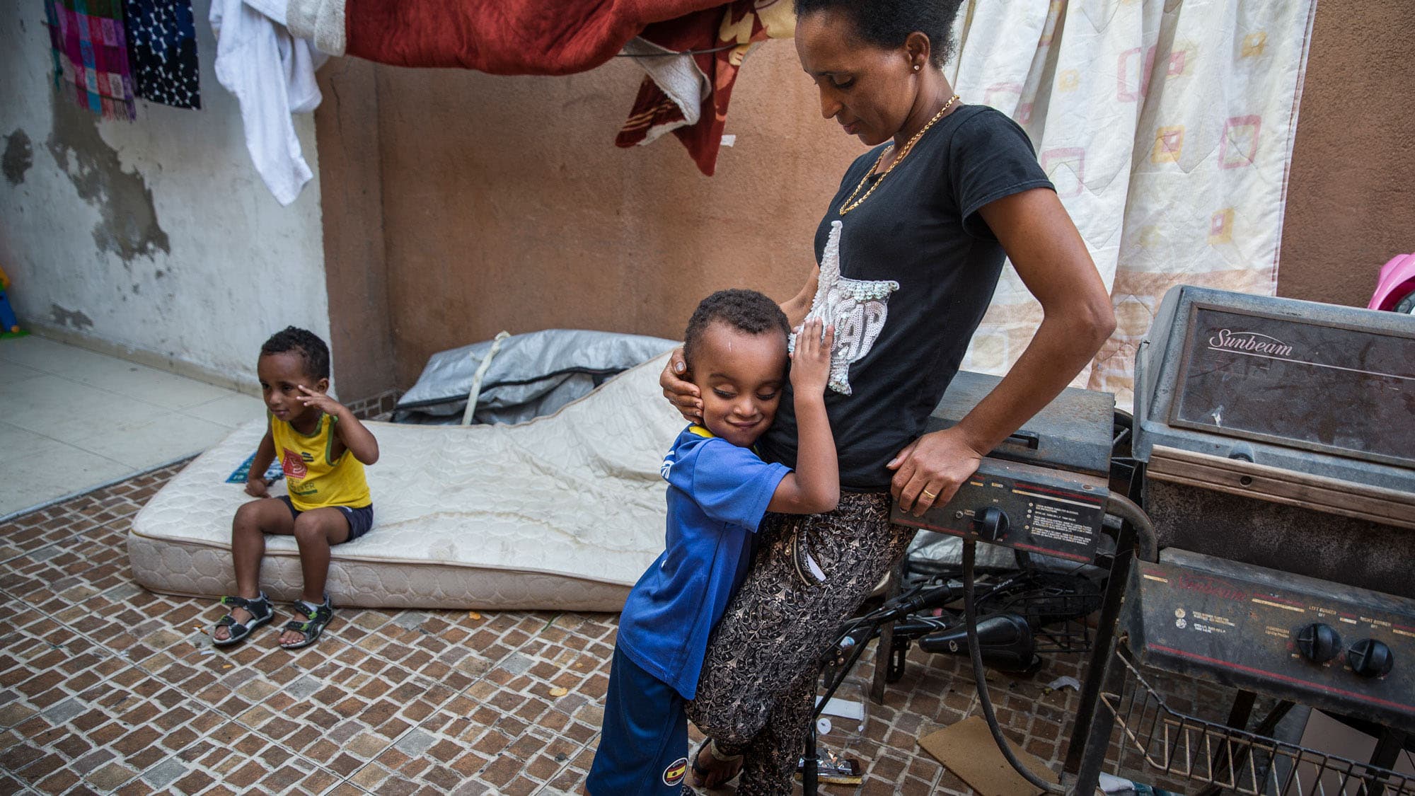 Brkitay Gebru with her sons, Tariki, 4, and Natanael, 3, in the courtyard of their building where immigrants from Eritrea and other countries rent rooms in Tel Aviv.