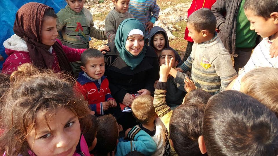 Children crowd around Zein in a camp in southern Aleppo.