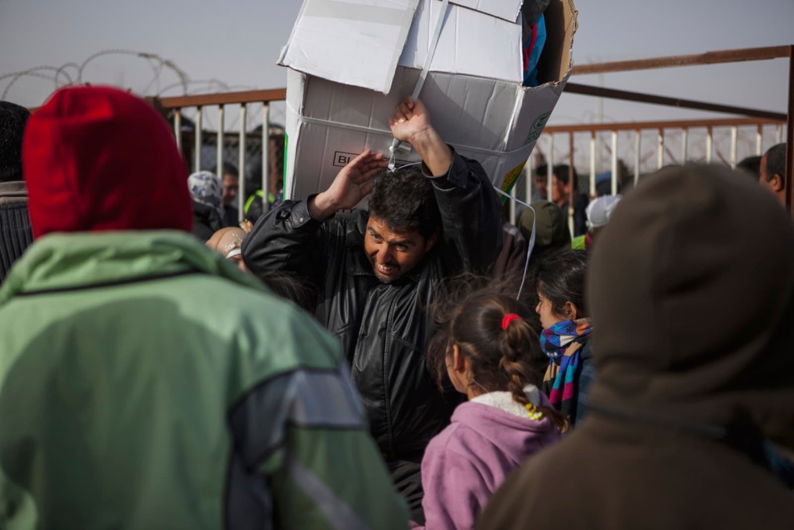 A man hauls a box of blankets during distribution hours in Zaatari refugee camp. First opened on July 23, 2012 as a temporary settlement in Jordan for Syrians fleeing conflict has since turned into a permanent fixture resembling a small city rather than a