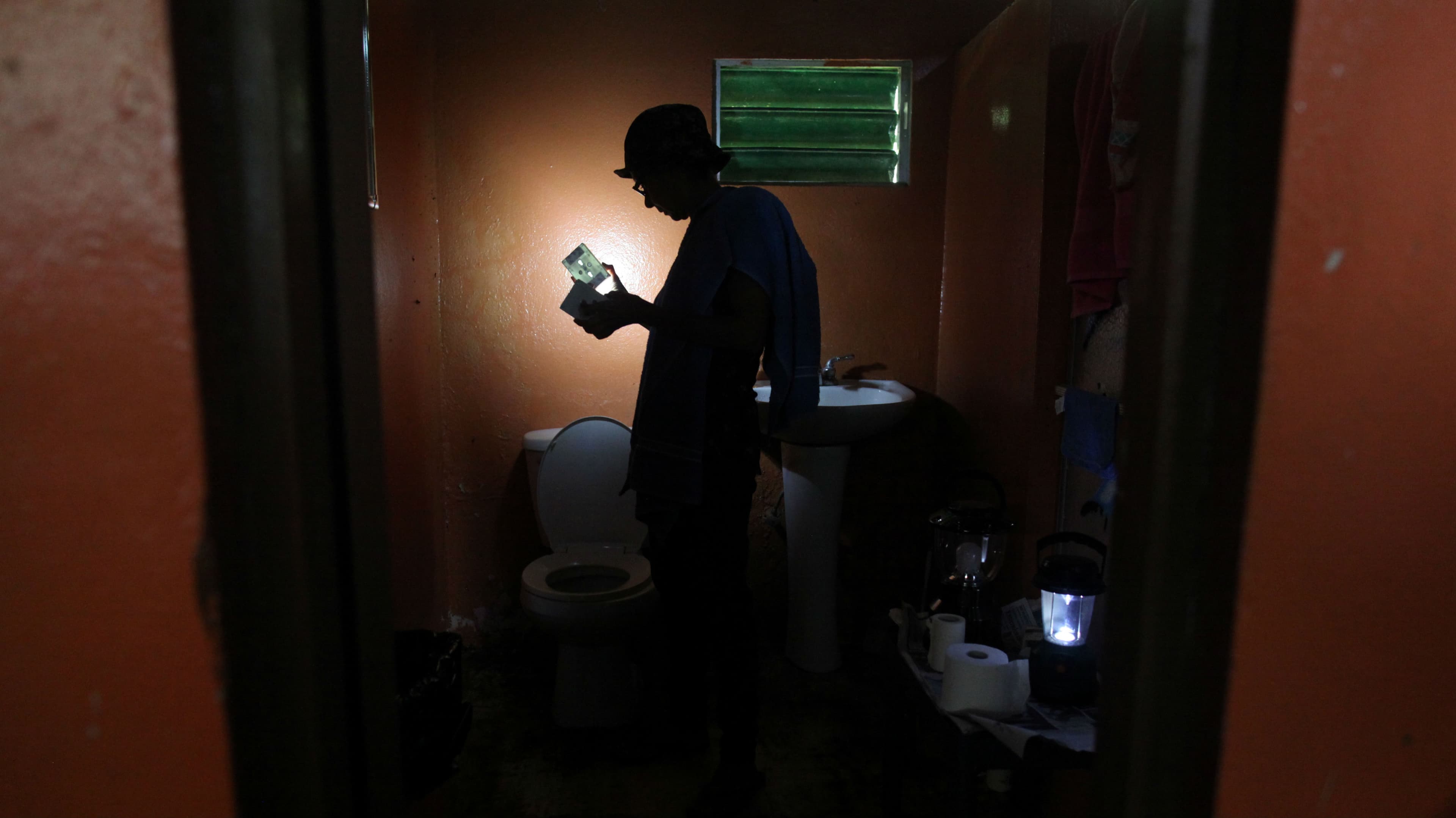 A woman uses a solar lamp inside the darkened bathroom of her home in Naguabo, Puerto Rico, on January 27, 2018.