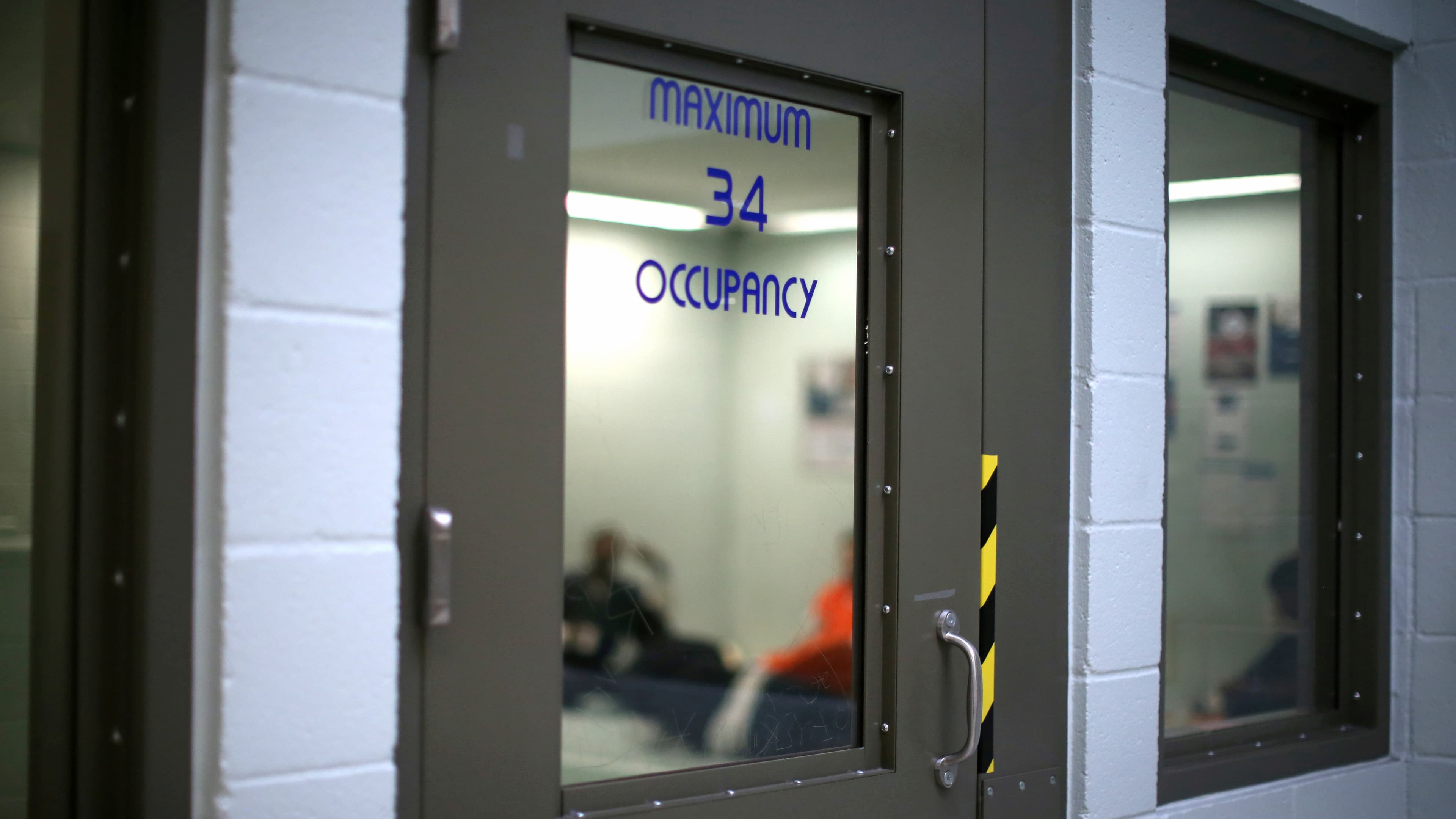 Immigrants sit in a cell for incoming ICE detainees at the Adelanto immigration detention center in Adelanto, California, April 13, 2017.