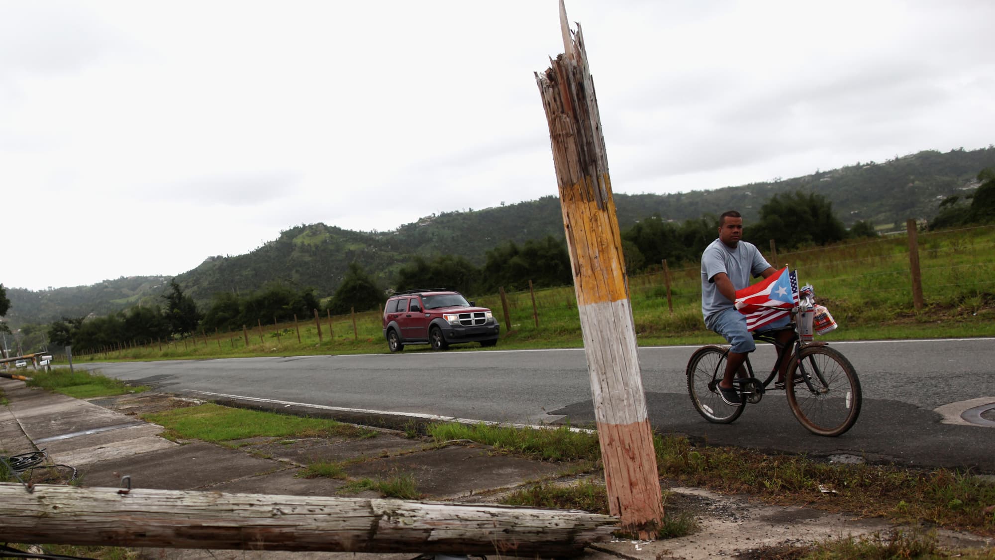 A man rides a bicycle past a collapsed utility pole after Hurricane Maria hit the island in September 2017.