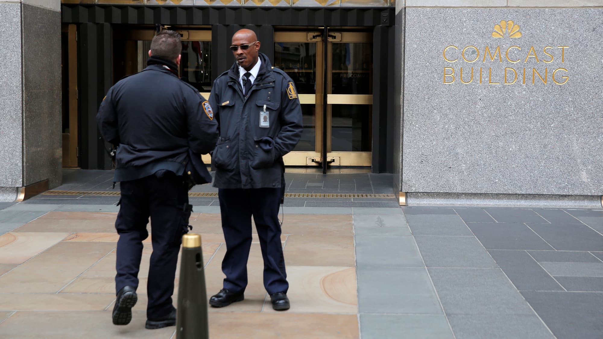 A police officer and security official stand outside 30 Rockefeller Plaza.