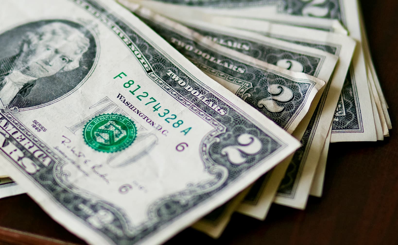 A pile of American two-dollar bills, which are relatively rare everywhere the currency is used.