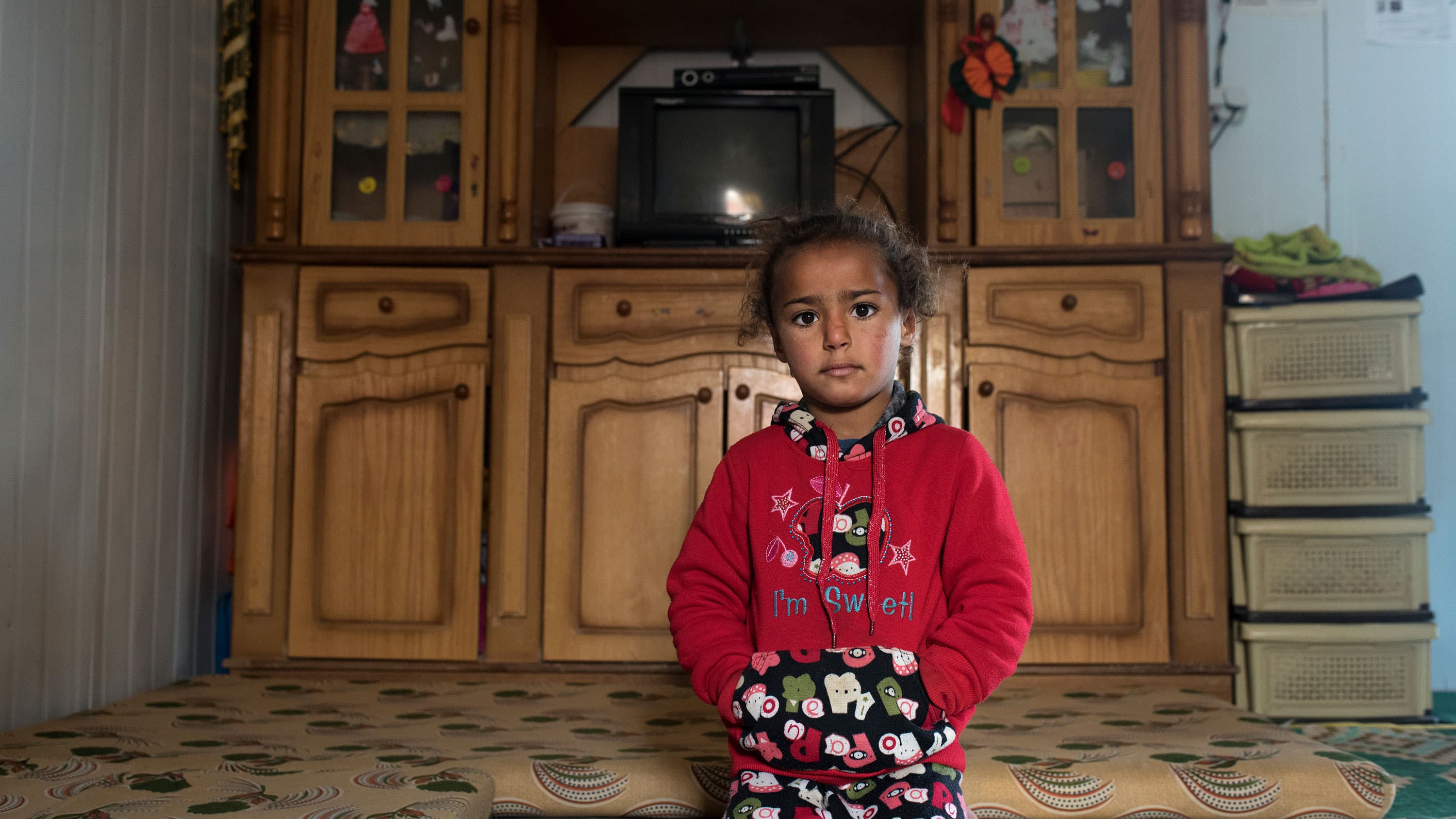 Um Ala's youngest daughter Hala sits in the family's metal shelter in Jordan's Zaatari refugee camp. Barely a year old when they left Syria, she doesn't remember the family's farm in Daraa's countryside.