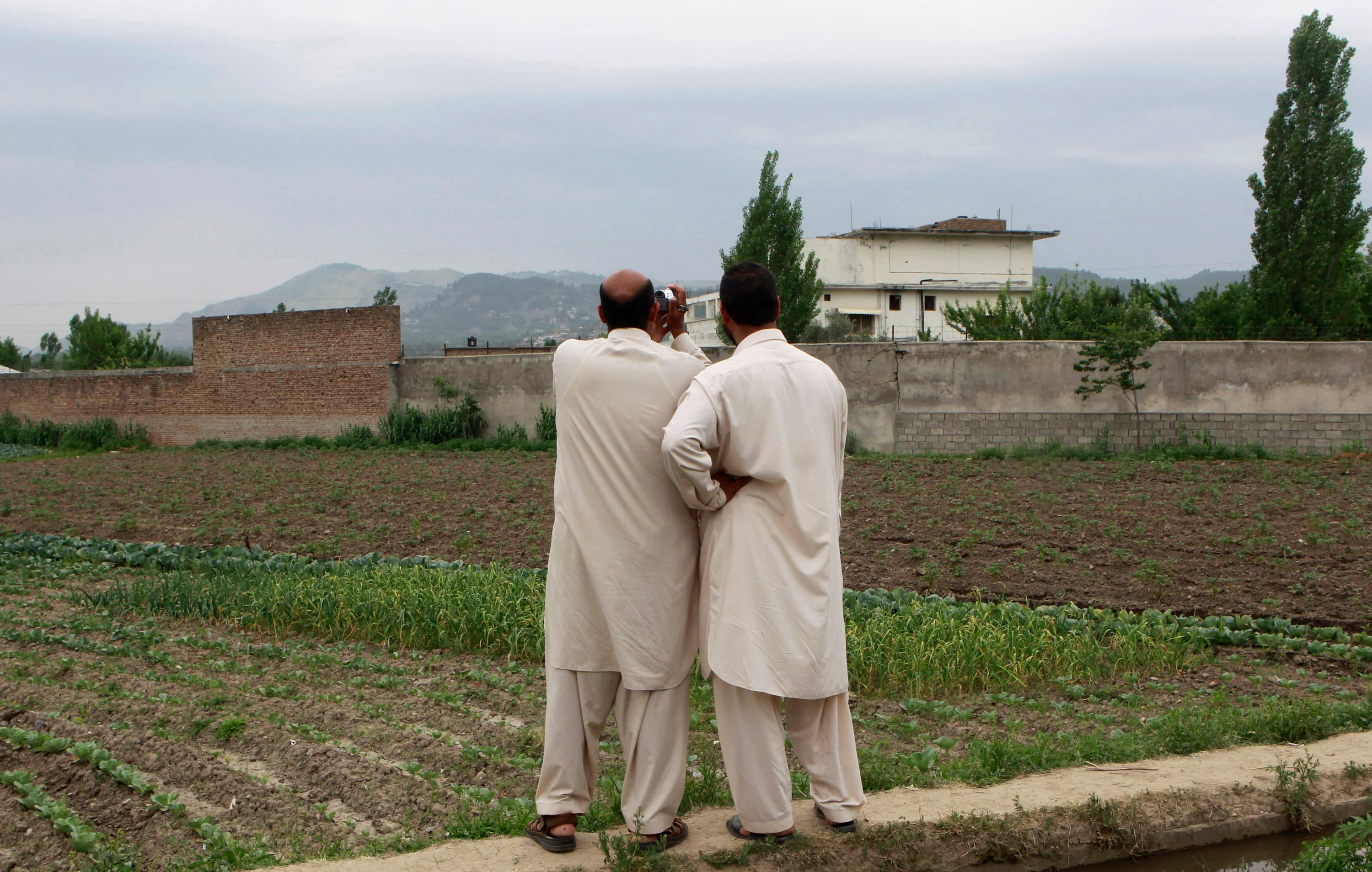 On May 5, 2011 in Abbottabad, Pakistan, residents record video footage of the compound where al-Qaeda leader Osama bin Laden was killed in a US special operations raid days earlier.