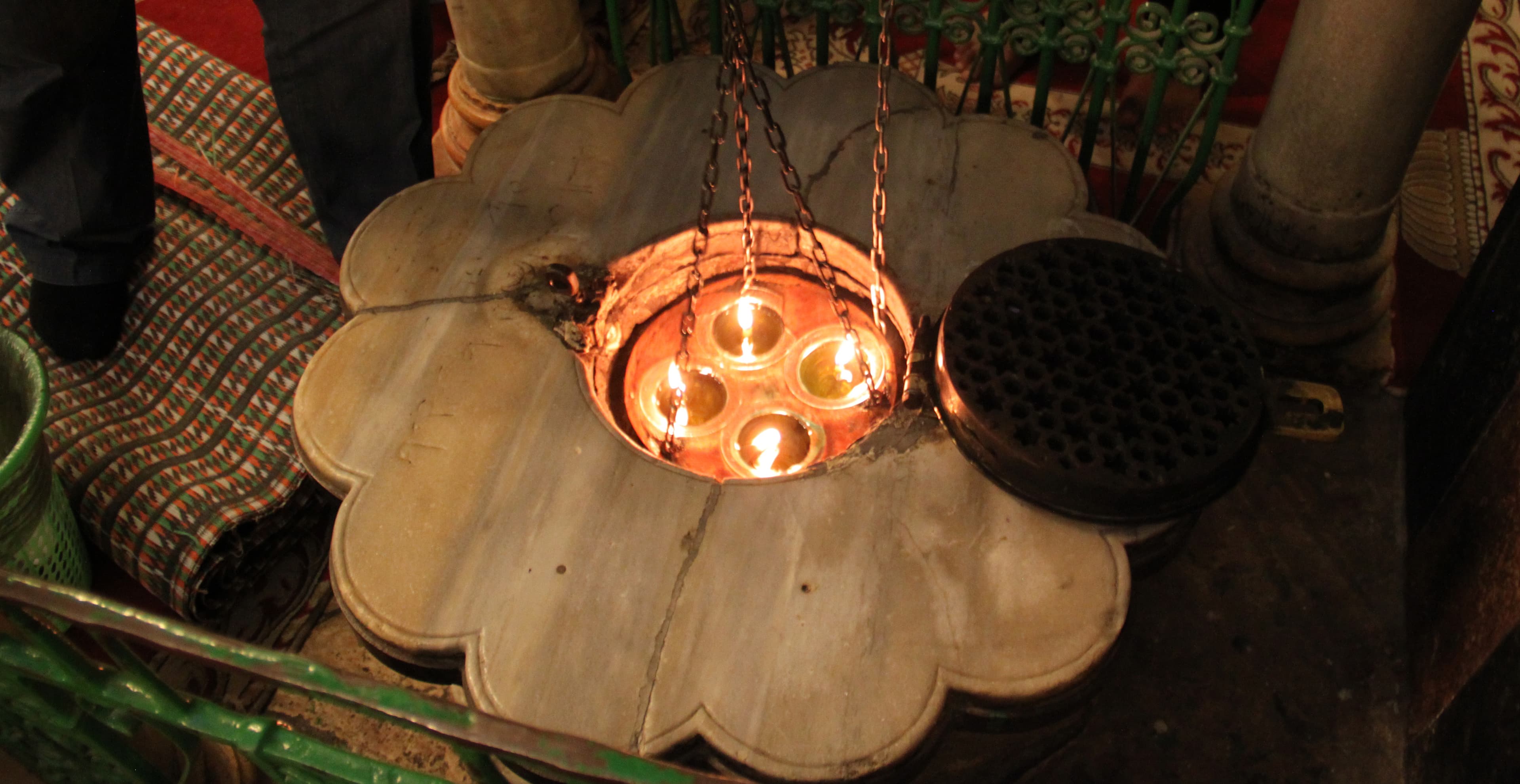 A mosque attendant lowers a candelabra into a narrow shaft on the Muslim side of the shrine to an underground cave. It's revered as the place where Muslims and Jews believe Ibrahim, or Abraham, is buried.