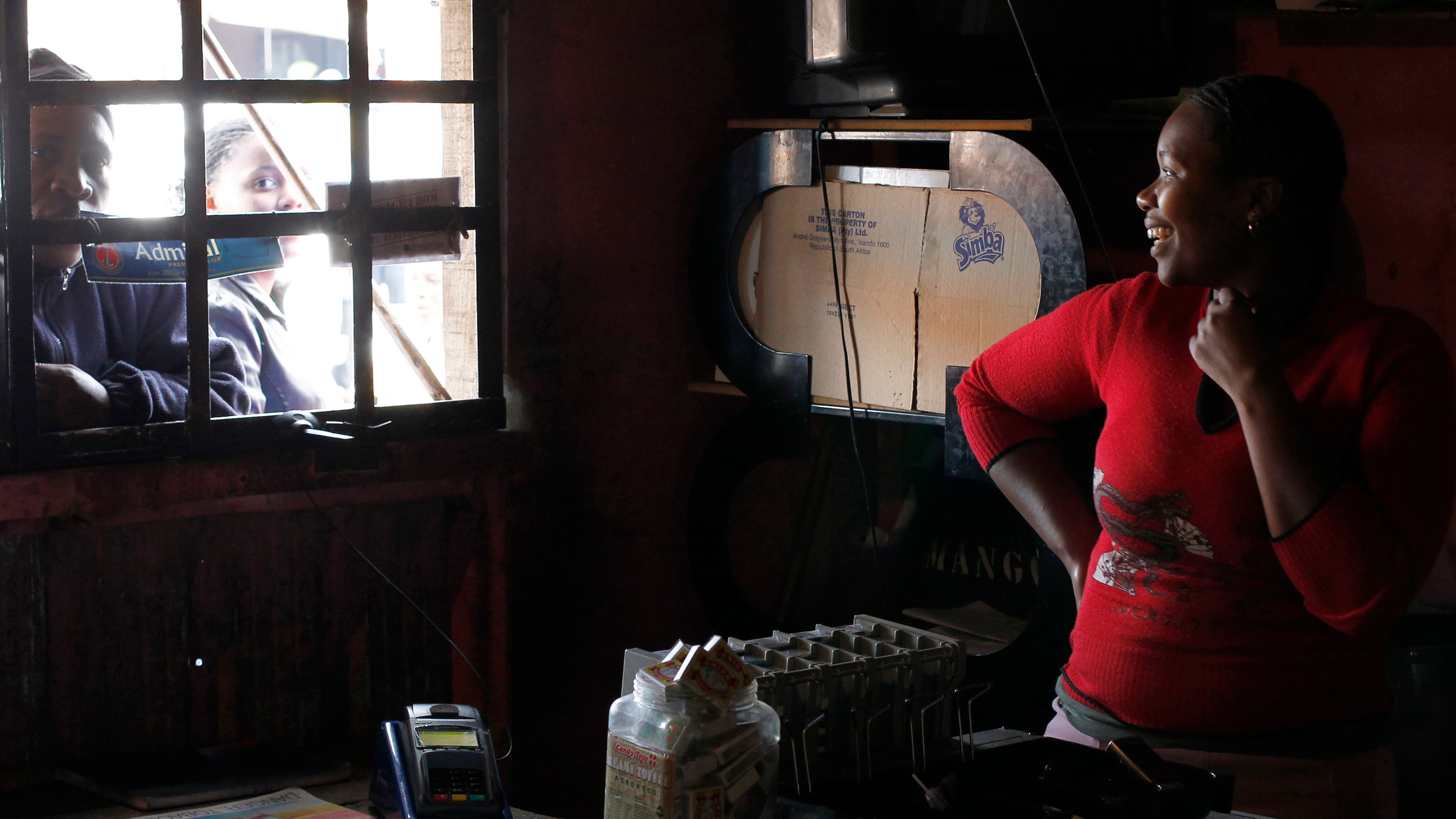 Trader Nono Dawane greets customers at her shop selling cigarettes and cold drinks, in Cape Town's Khayelitsha township.