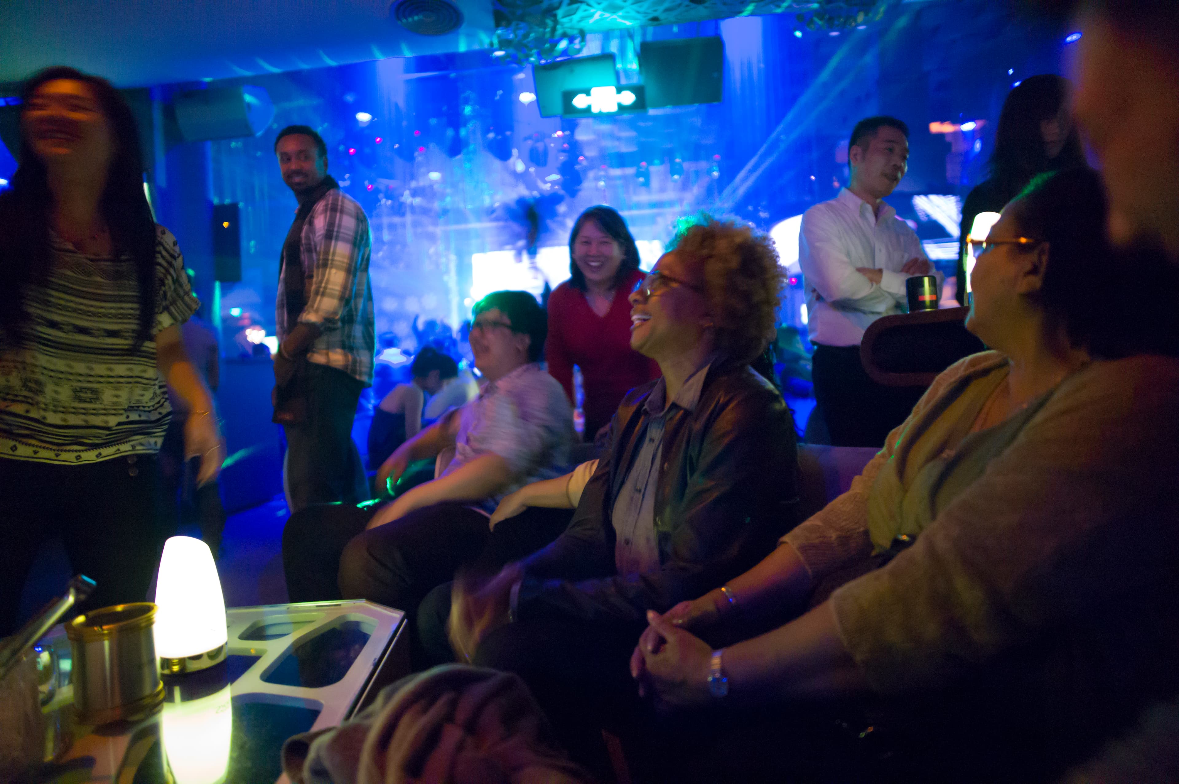 Woman seated in club with people walking around her