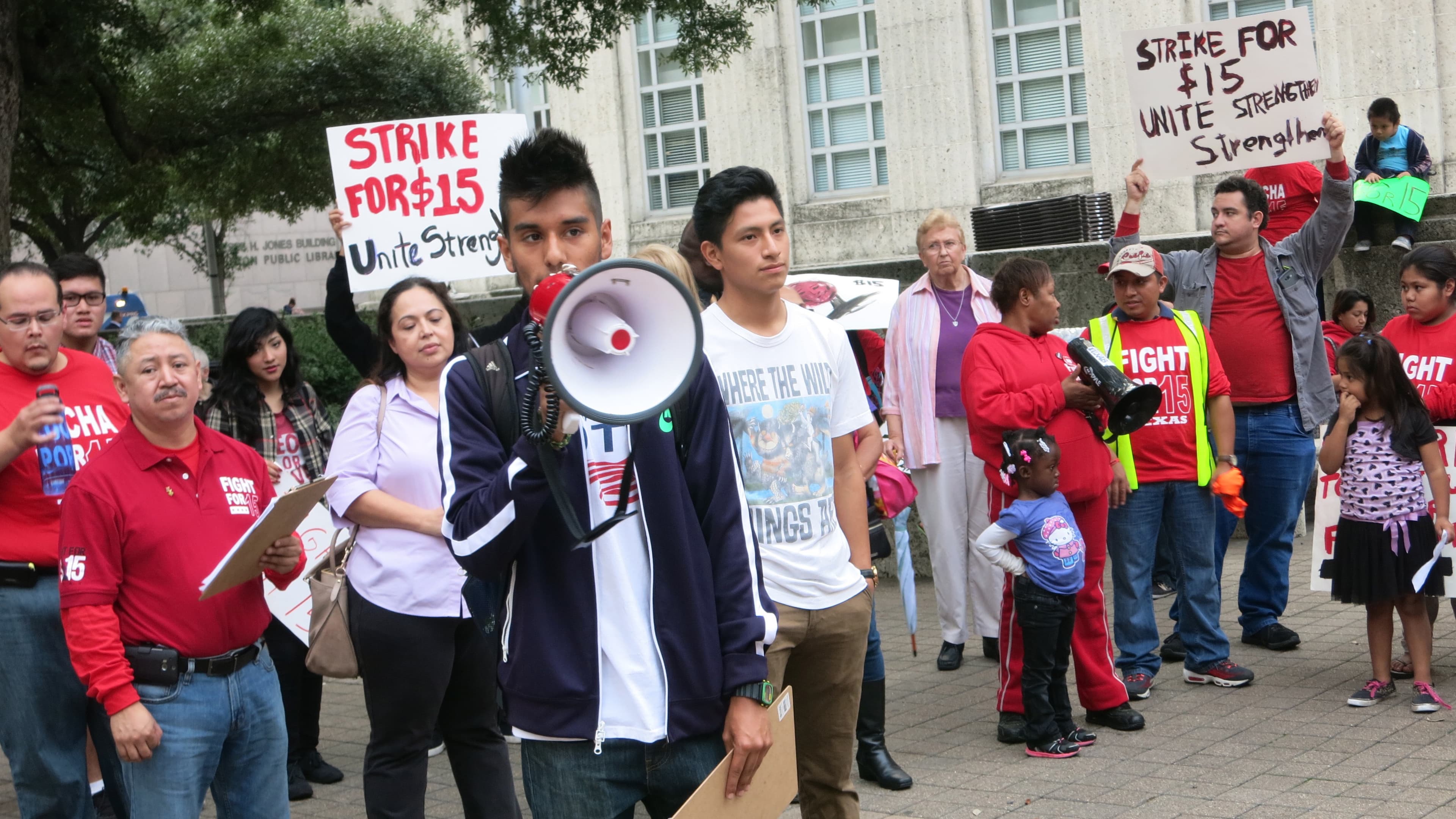 Daniel Meza holds a bullhorn as Mario Sidonio, to his right, waits his turn to speak at a rally in front of Houston's City Hall.