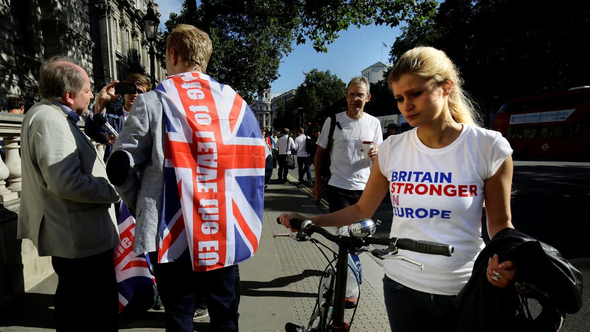A vote remain supporter walks past a vote leave supporter outside Downing Street in London after Britain voted to leave the European Union.
