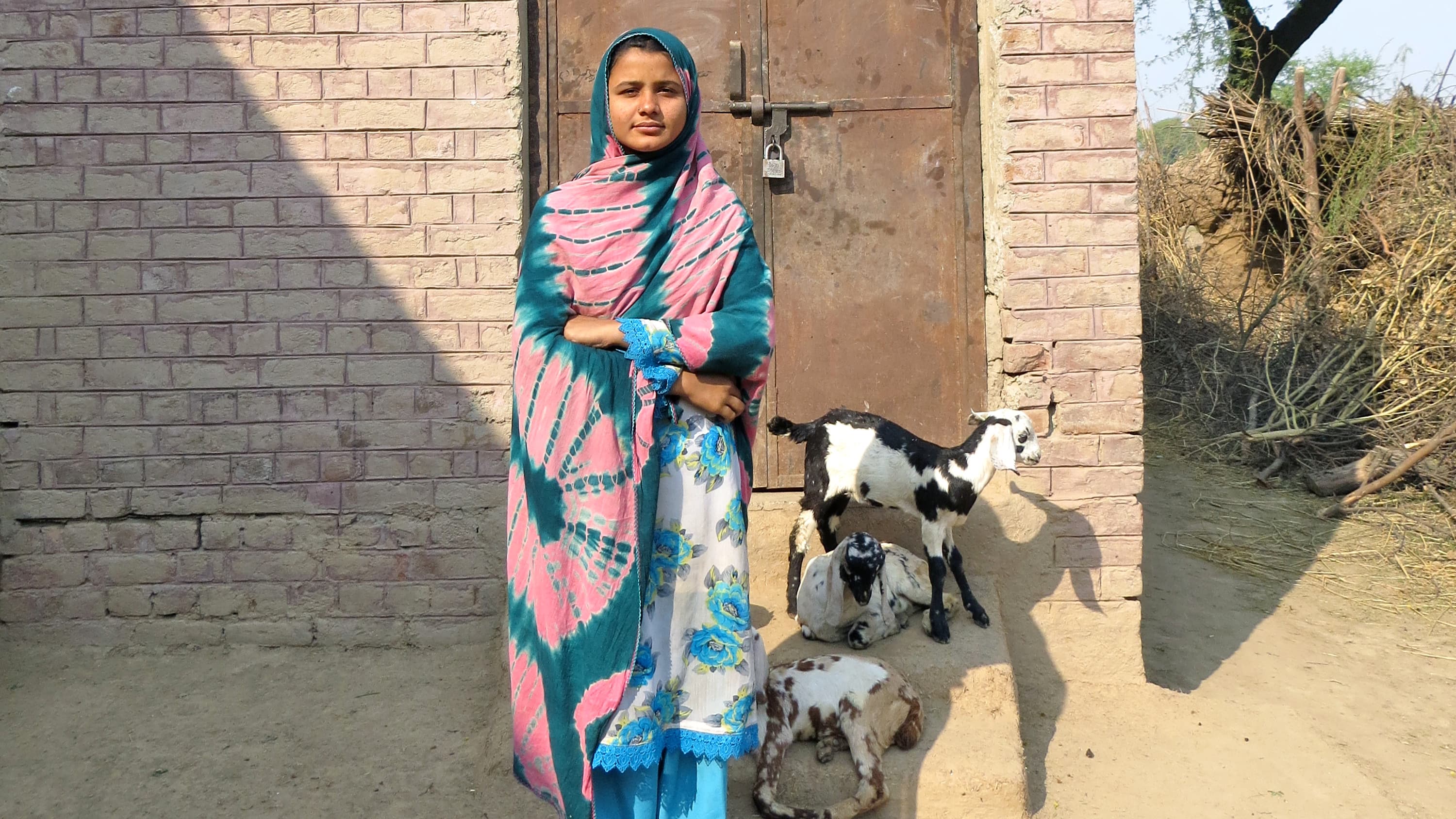 Uzma Ahmed Ali stands in the courtyard of the former girls' school, which shut down several years ago. She now travels an hour to study – something few girls in her village are able to do.