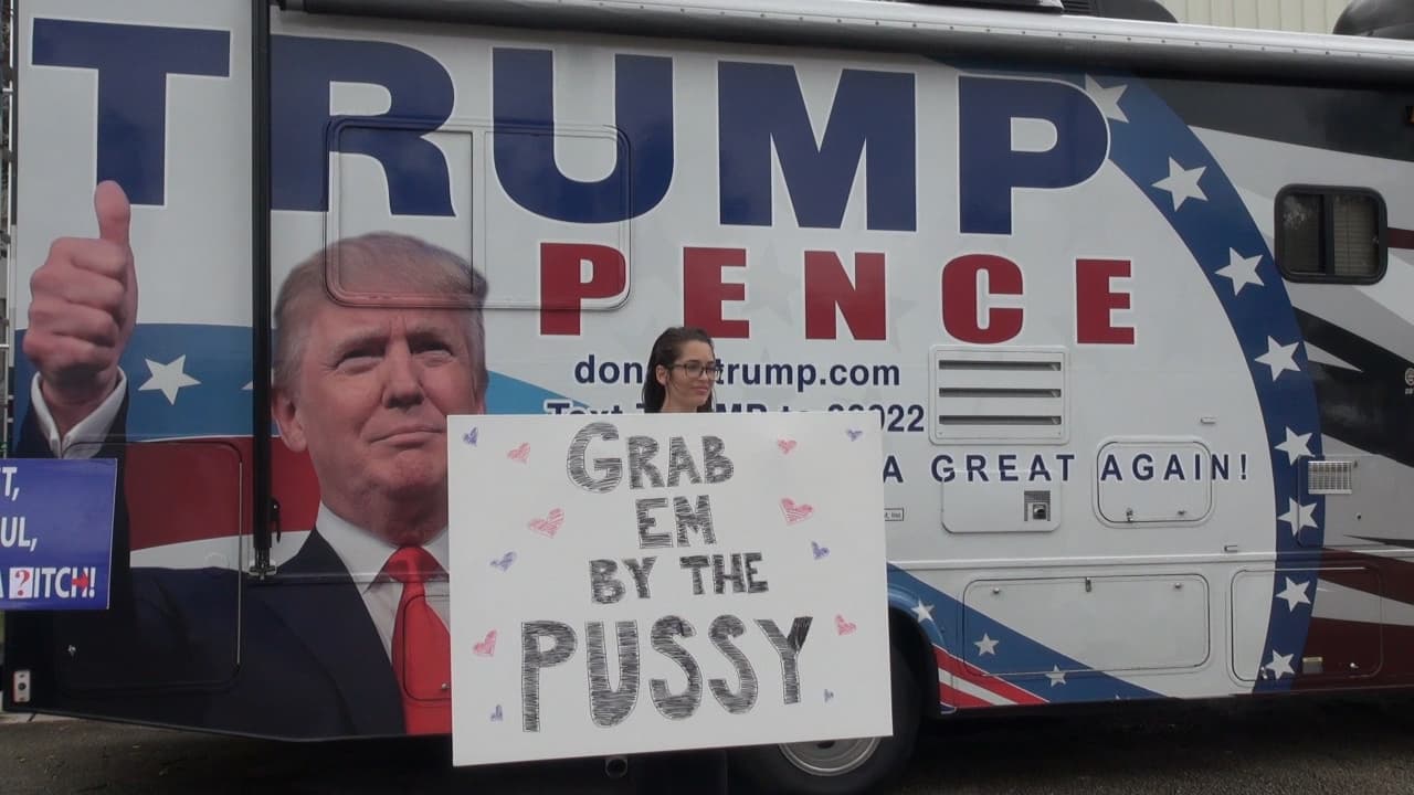 Young female Trump supporter holds sign "Grab em by the pussies" at rally