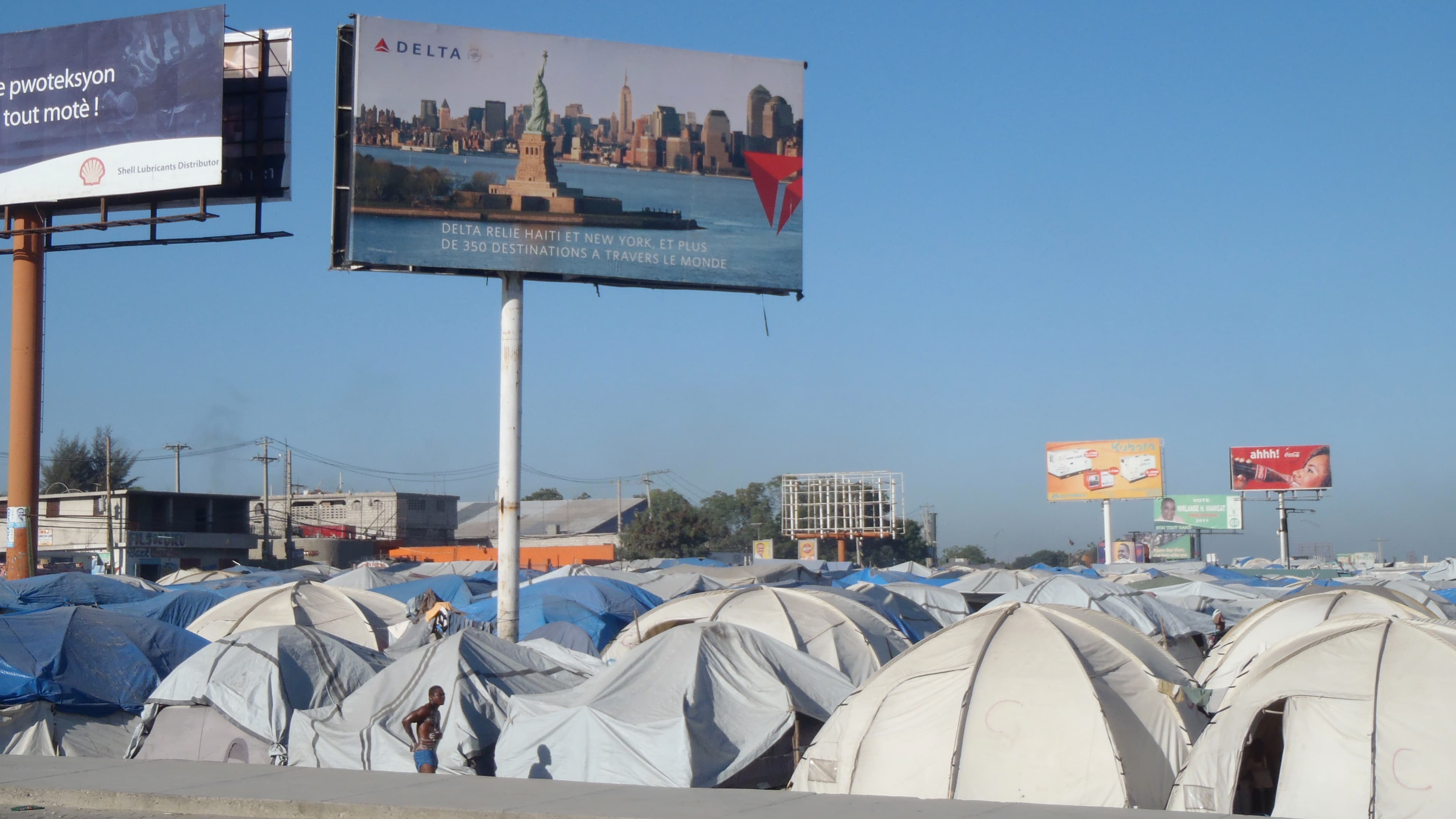 A Haitian city, juxtaposed with a billboard featuring the Statue of Liberty
