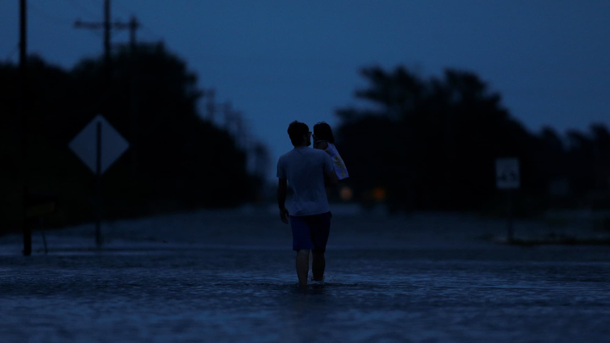Ethan holds his 2-year-old daughter Zella as they walk through flood waters from Tropical Storm Harvey in Calcasieu Parish, Louisiana, on August 29, 2017.