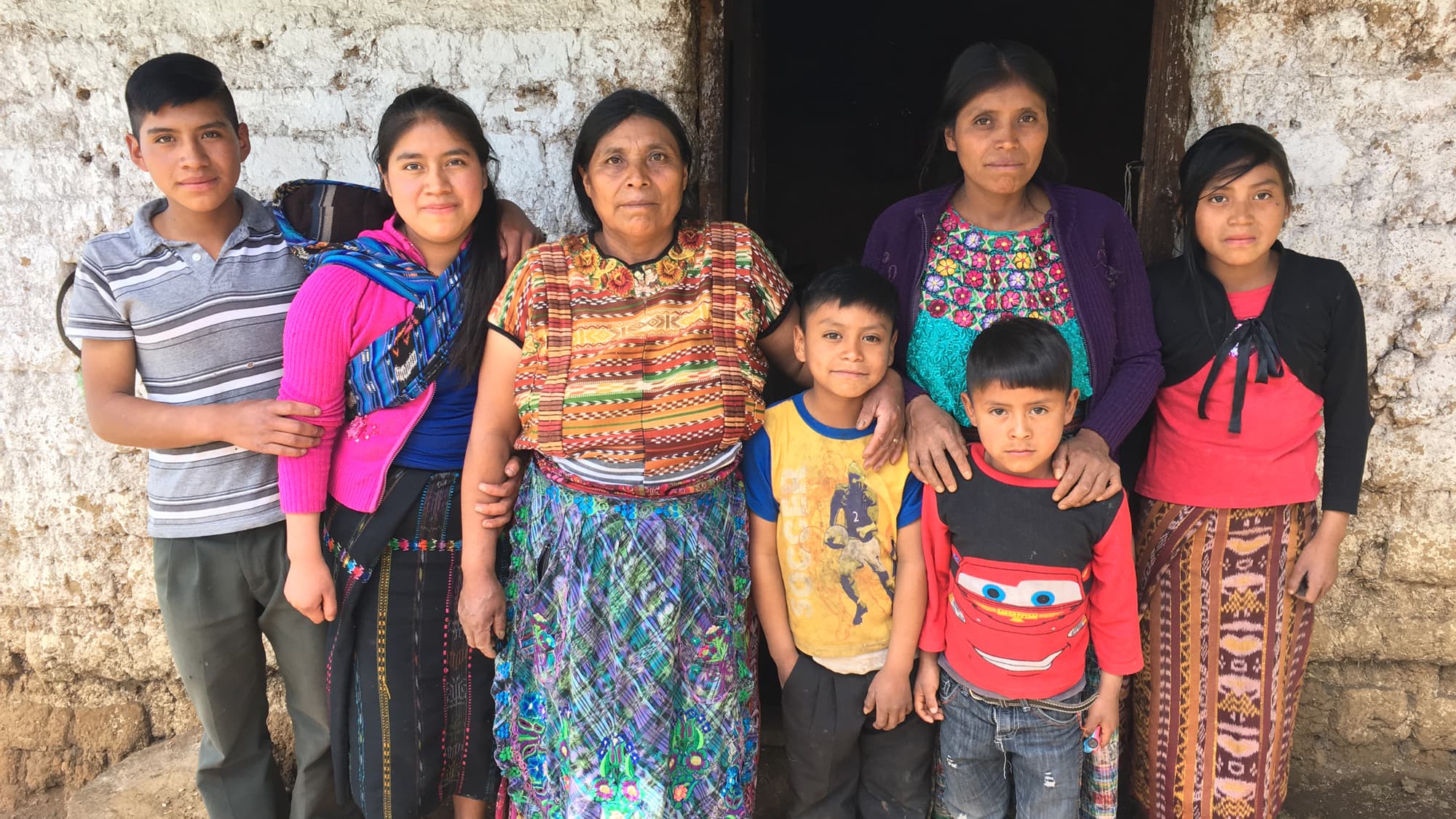 Elvira Mauricia Diaz standing center with her family against a stone wall backdrop.