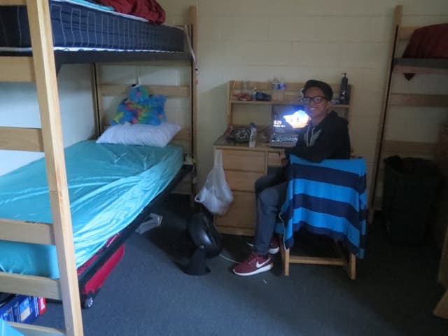 Young man in front of his desk in a dorm room
