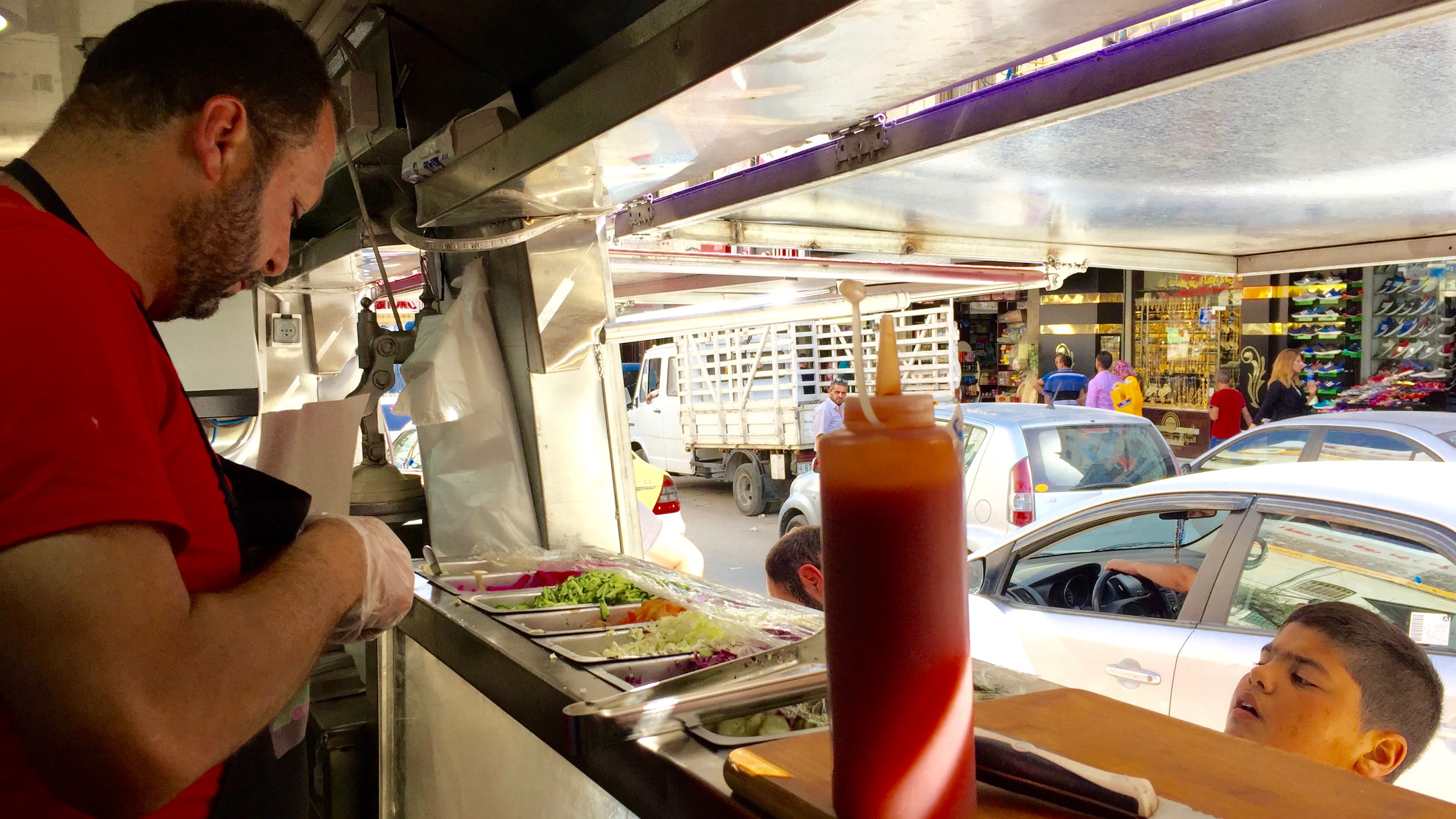 Khaldoun Barghouti, an ex-prisoner-turned-entrepreneur, serves up a chicken sandwich for a young customer in the West Bank city of Ramallah.